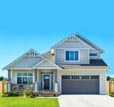 Front view of a modern two-story house with a garage, lawn, and clear blue sky.