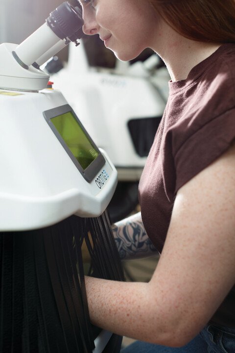 A woman looking through a microscope in a laboratory.