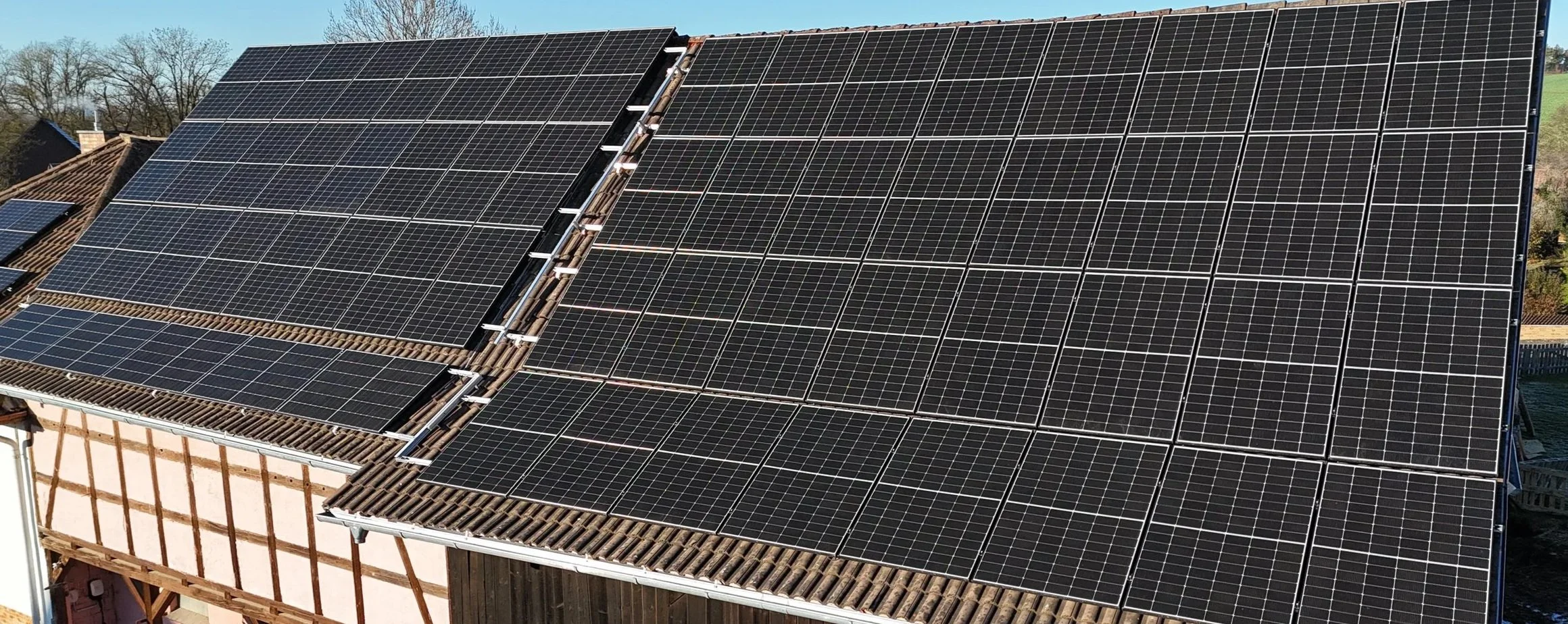 Dach mit zahlreichen schwarzen Solarzellen während eines sonnigen Tages.