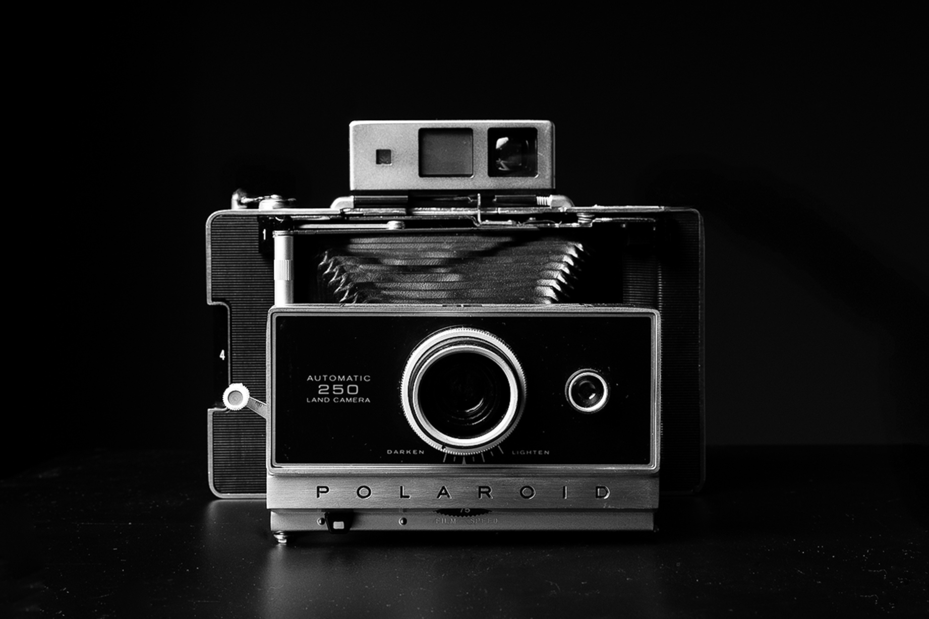 Black and white photograph of a vintage Polaroid Land Camera with a dark background.