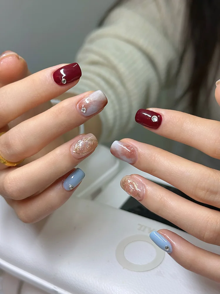Iris nail art at Serene Nail Club NYC: Red, light blue and glittery gold nails with rhinestones