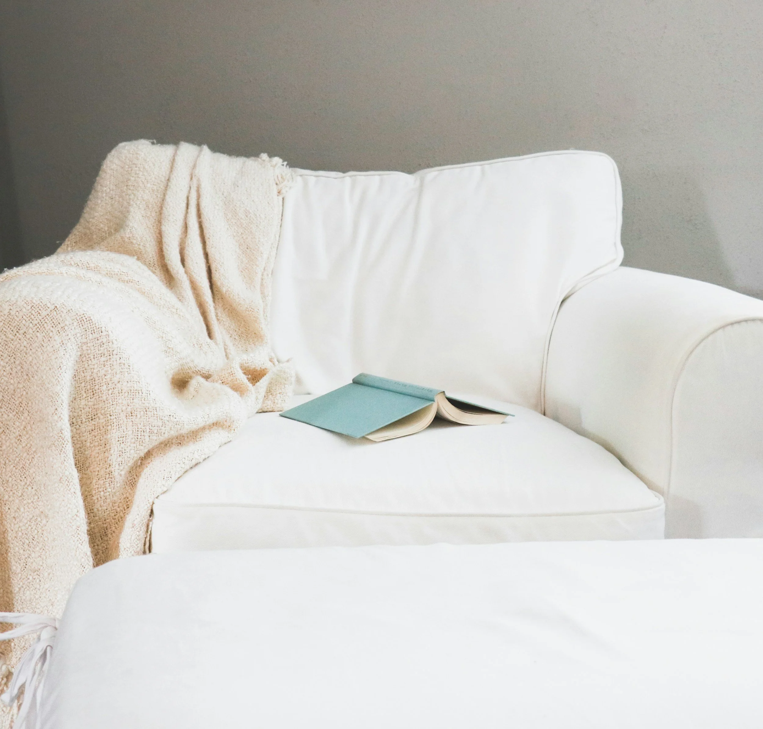 Comfortable therapy office couch with a book, creating a safe and welcoming space for somatic therapy, trauma recovery, and emotional healing.