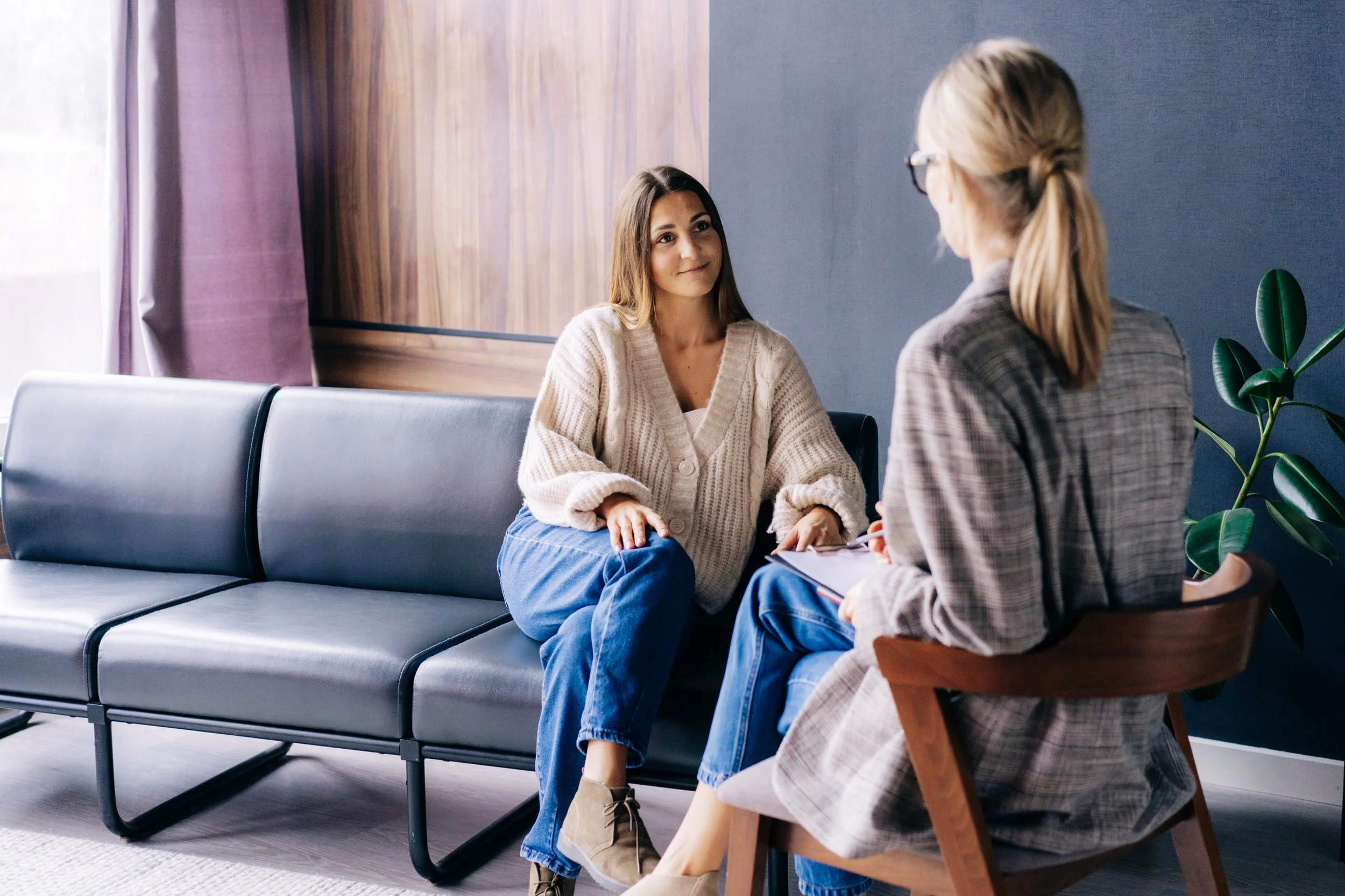 Client sitting in a therapy office during a trauma counseling session in a safe, supportive environment