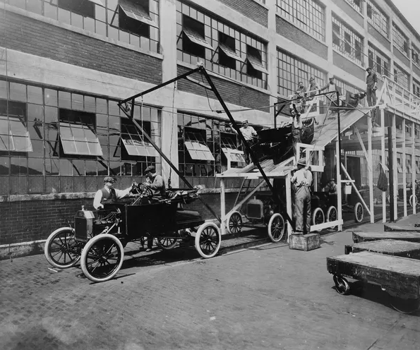 Vintage Ford Model T automobiles lined up outside the Ford Motor Company factory in Detroit during the early days of America’s automotive industry, illustrating the rise of Detroit as the Motor City.