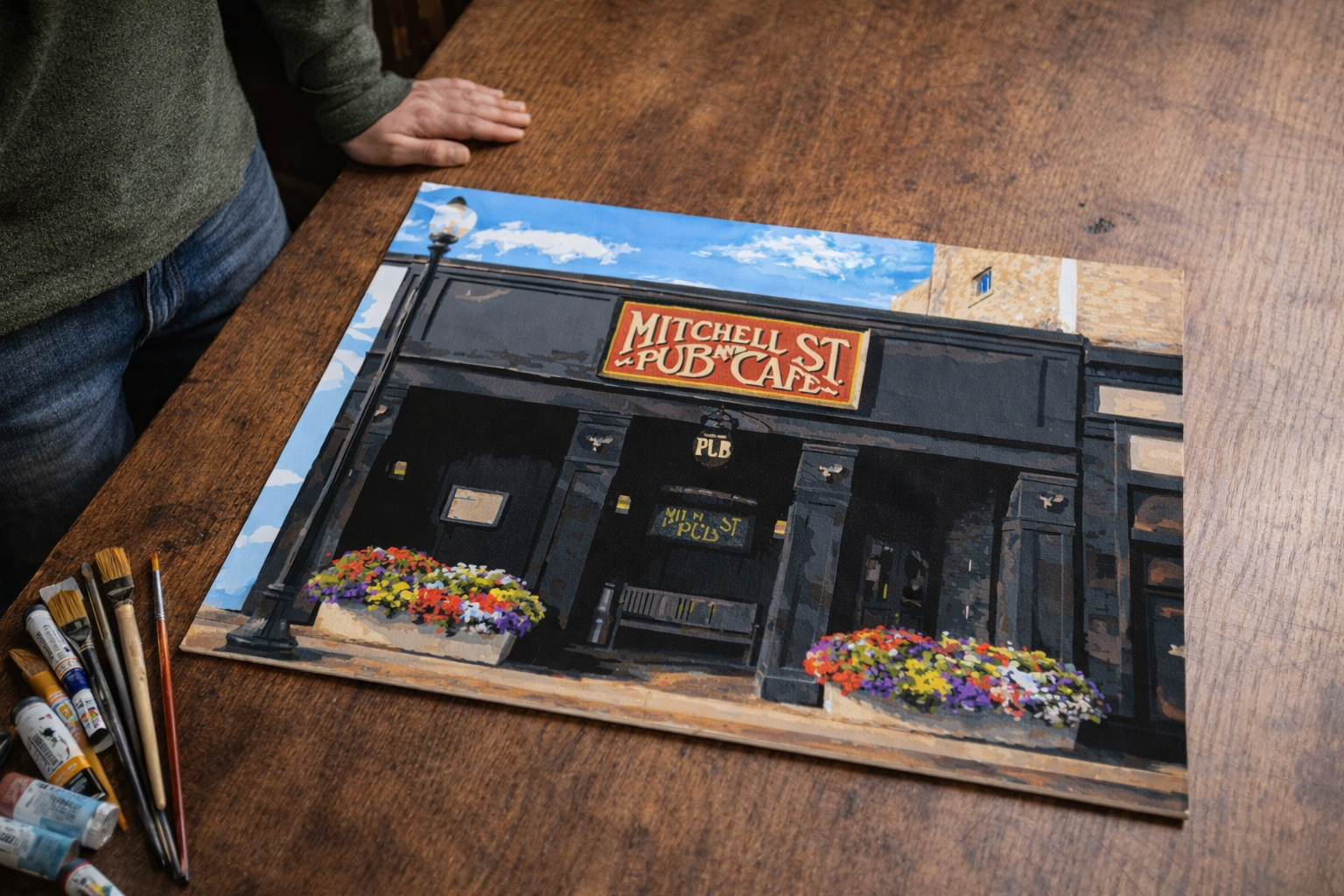 Mitchell Street Pub Summer Front showcases the historic Mitchell Street Pub on Mitchell Street in downtown Petoskey, Michigan, portrayed on a bright summer day and capturing the character, history, and unmistakable presence of one of Petoskey’s most 