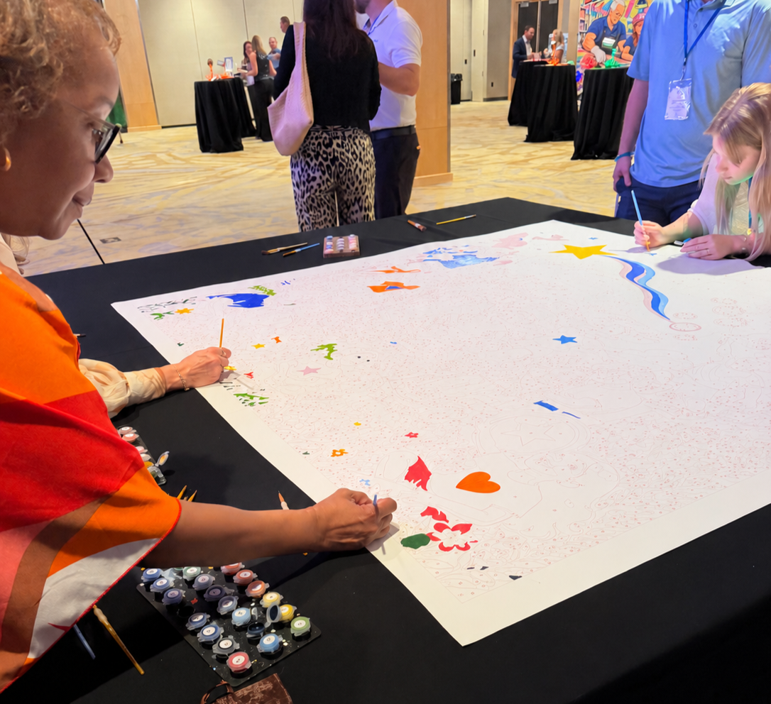 Attendee painting a custom paint-by-number community mural by Mitten Masterpiece