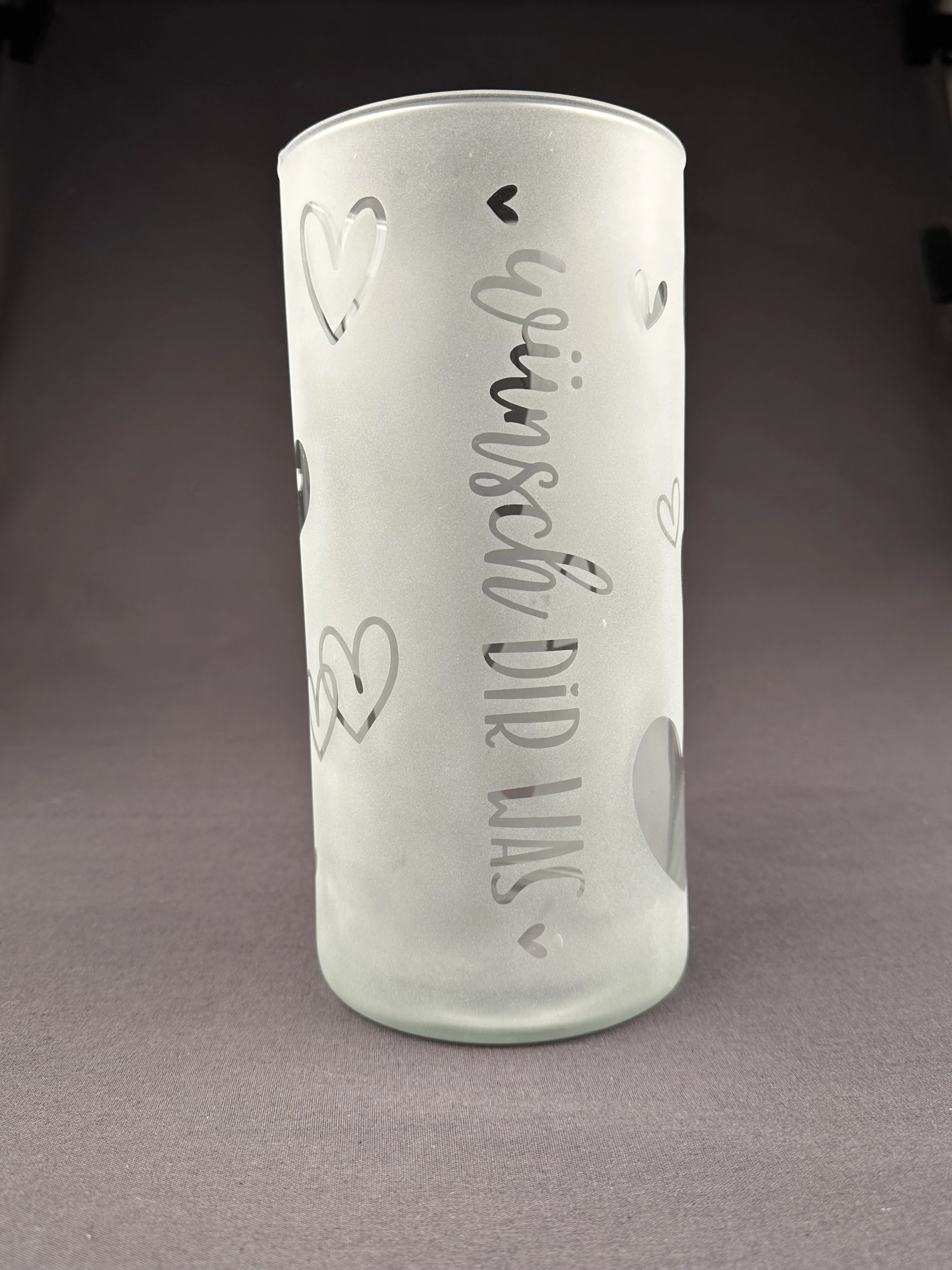 Ein durchsichtiger Kerzenhalter mit Herzmotiven und der Inschrift 'een y 'n aparte vrouw was' in cursiver Schrift.