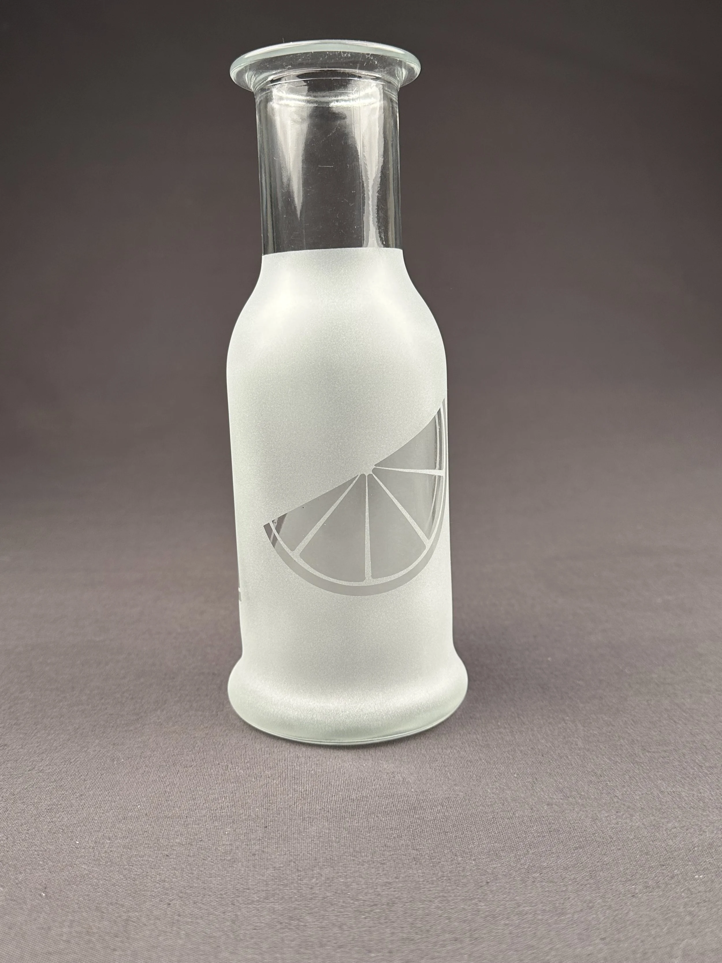 Eine Glasflasche mit einem Zitronen-Symbol, die auf einem grauen Hintergrund steht.