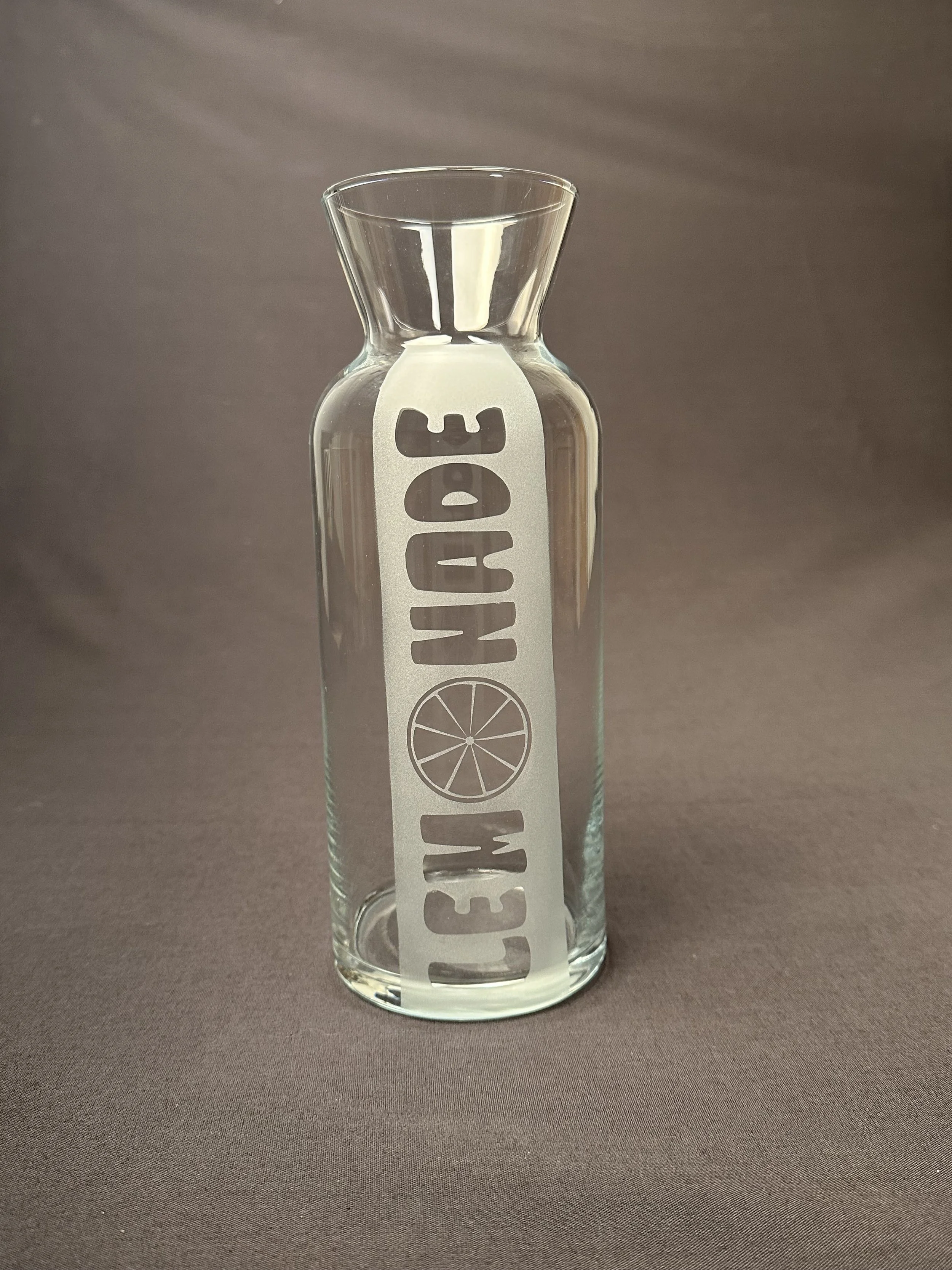 Eine Glasvase mit einem Etikett, auf dem 'CITRONENLIMON' steht, und einer Zitronenscheibe in der Mitte.