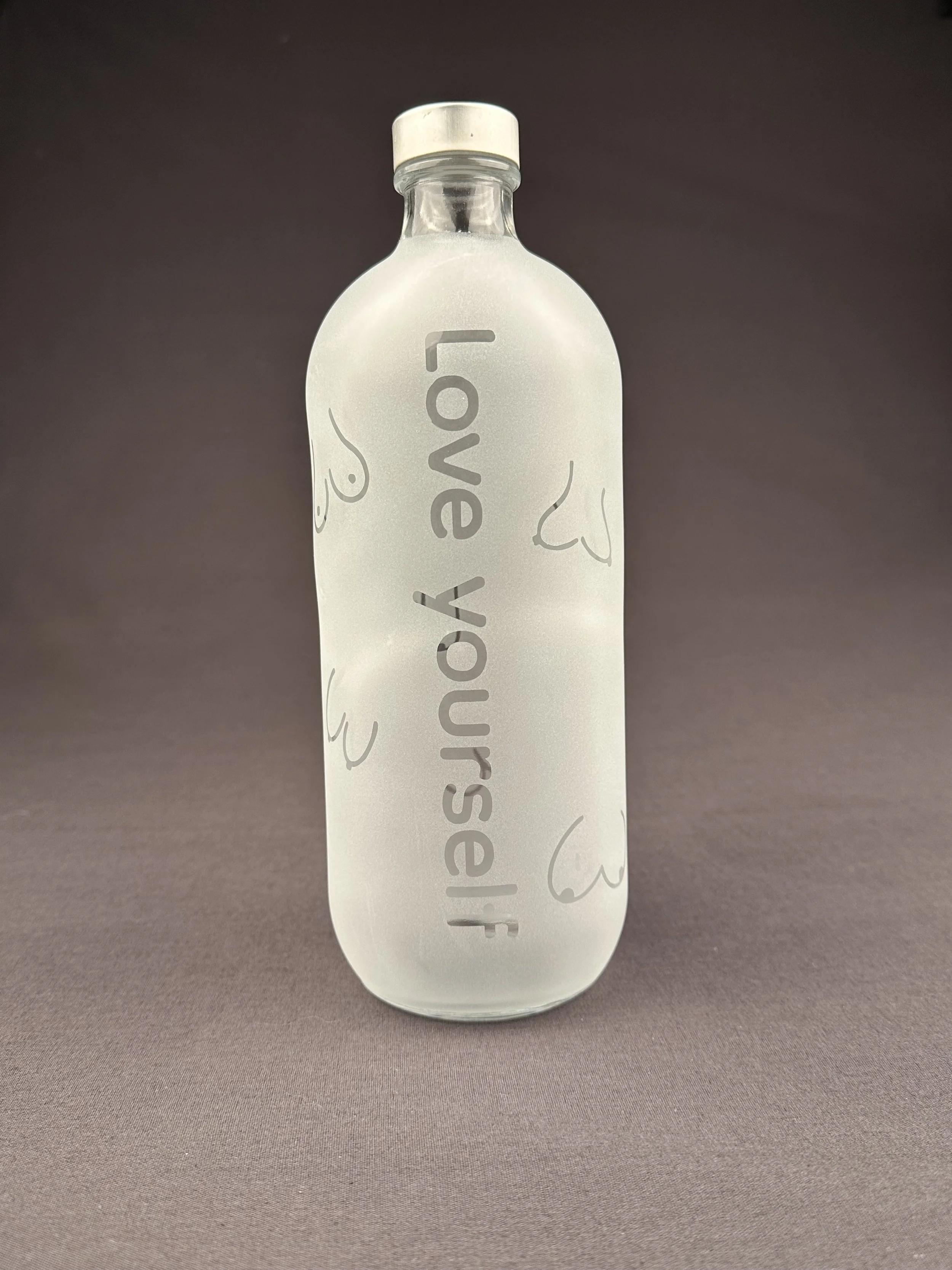 Transparente Flasche mit silberner Kappe, bedruckt mit 'love yourself' und Herz-Skizzen