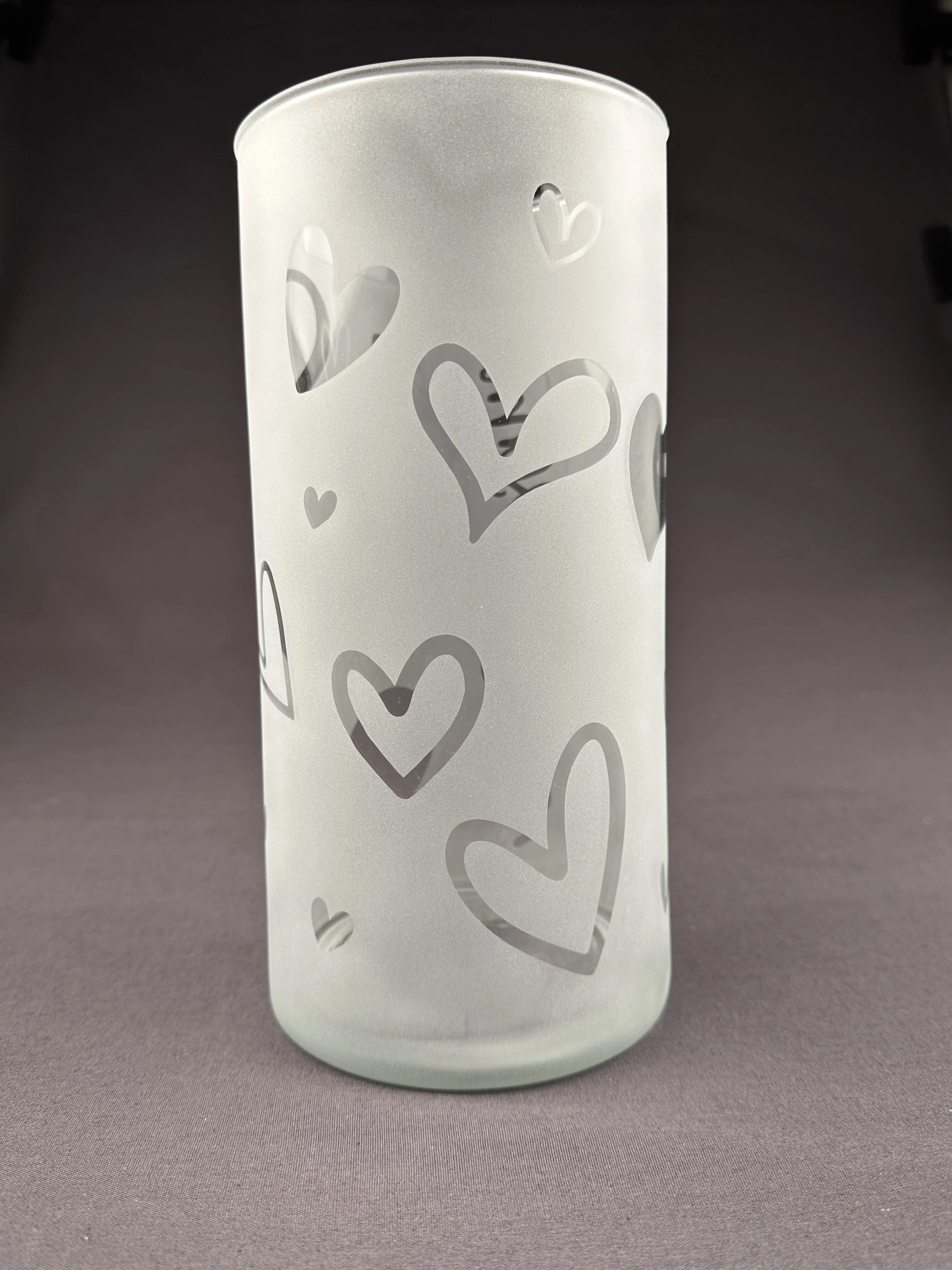 Heller Glas mit Herzmustern auf dunklen Hintergrund.