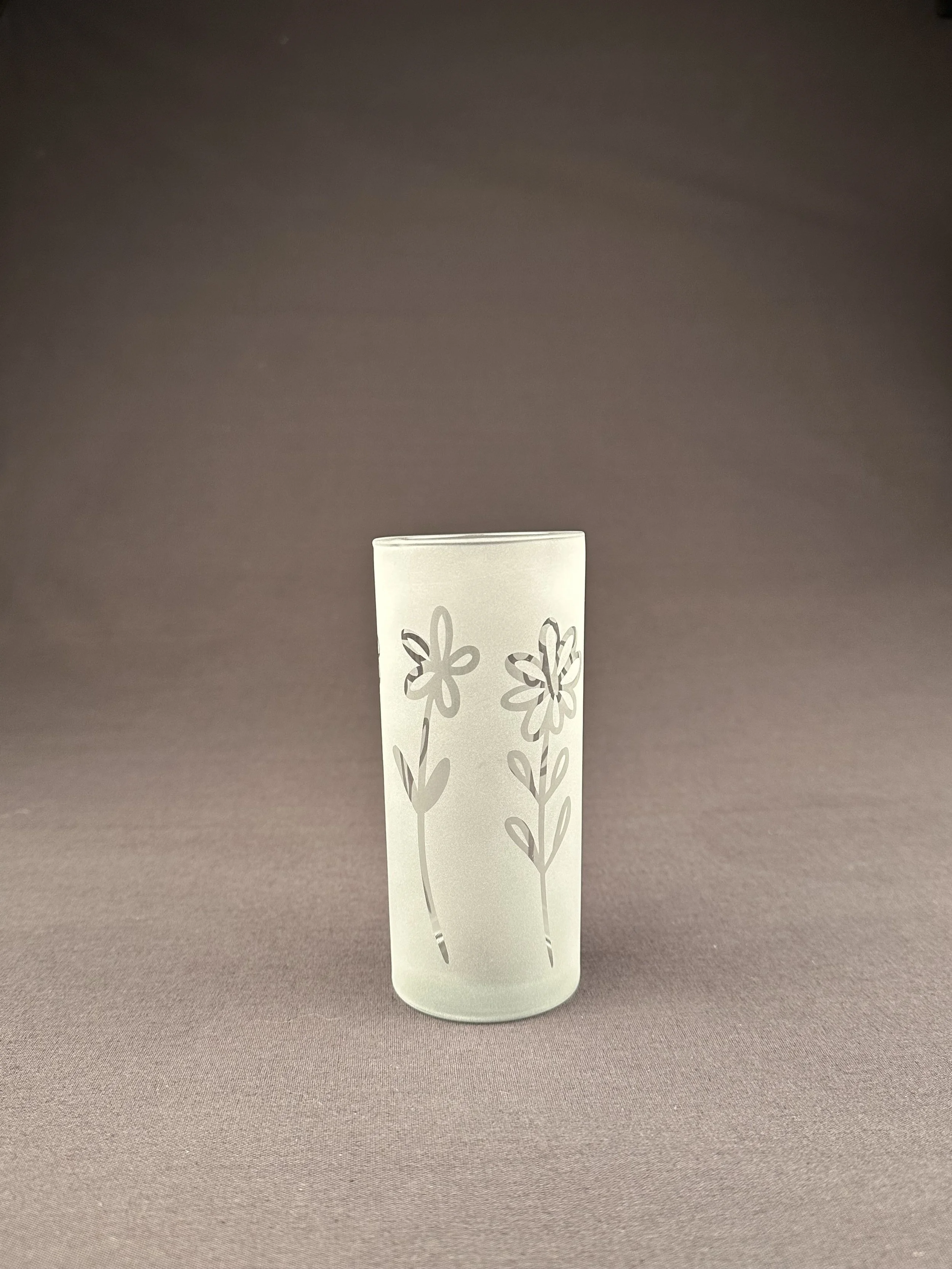 Transparenter Glas mit Blumenmuster auf braunem Hintergrund.