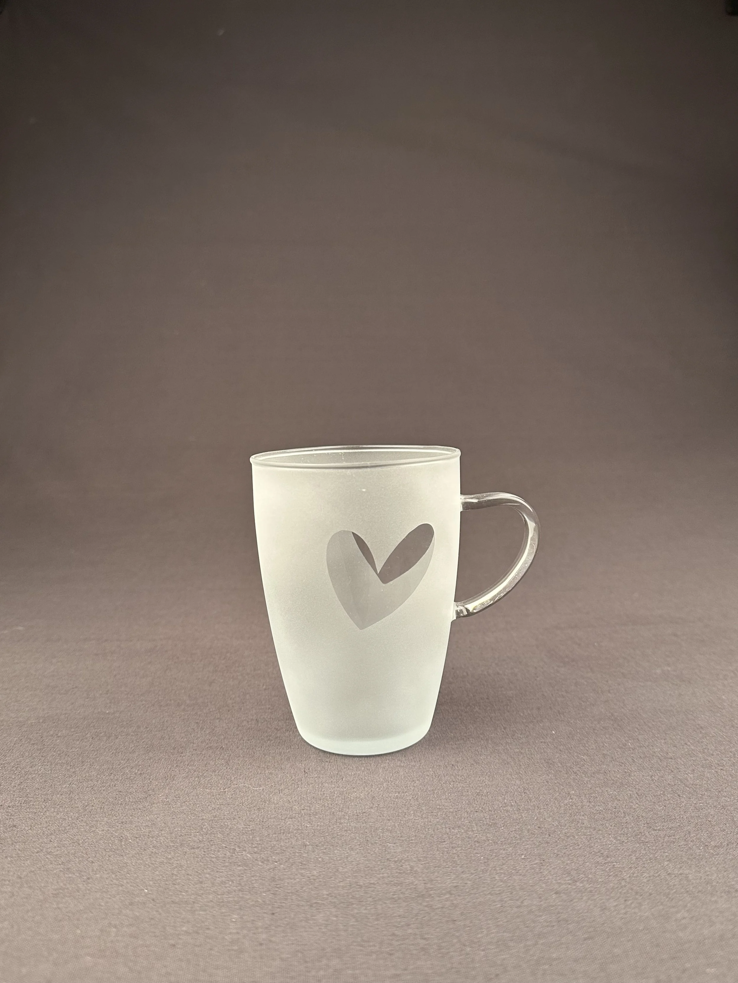 Frosted Glas mit Herzmotiv auf braunem Hintergrund.