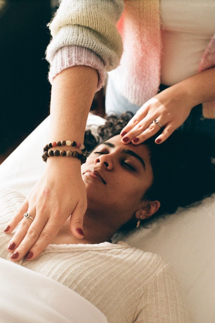 Person receiving a relaxing head massage from another individual lying on a bed.