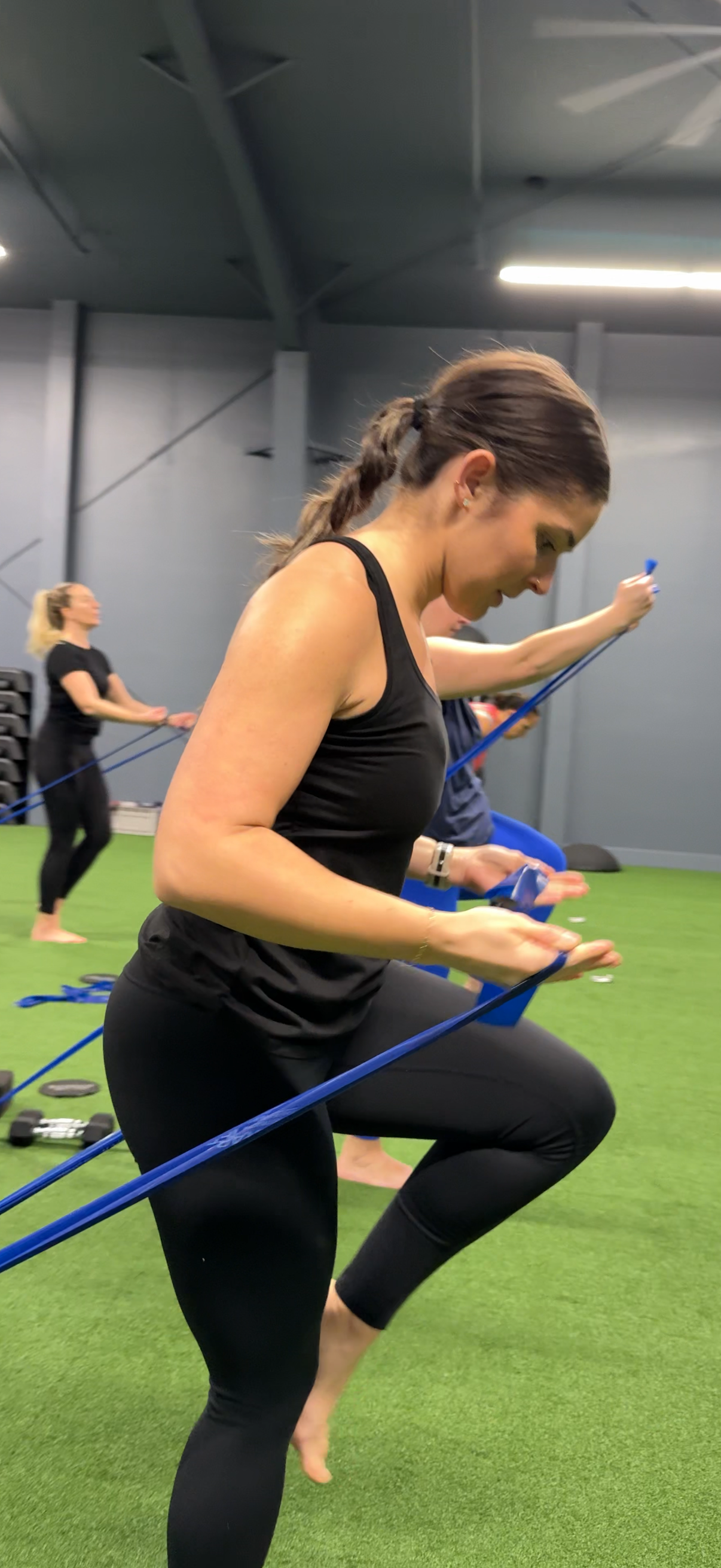 Jasmin, a Temple Instructor is in black workout clothes performing a balance exercise with resistance bands at Temple Fitness NW, a fitness studio in Bellingham, WA.