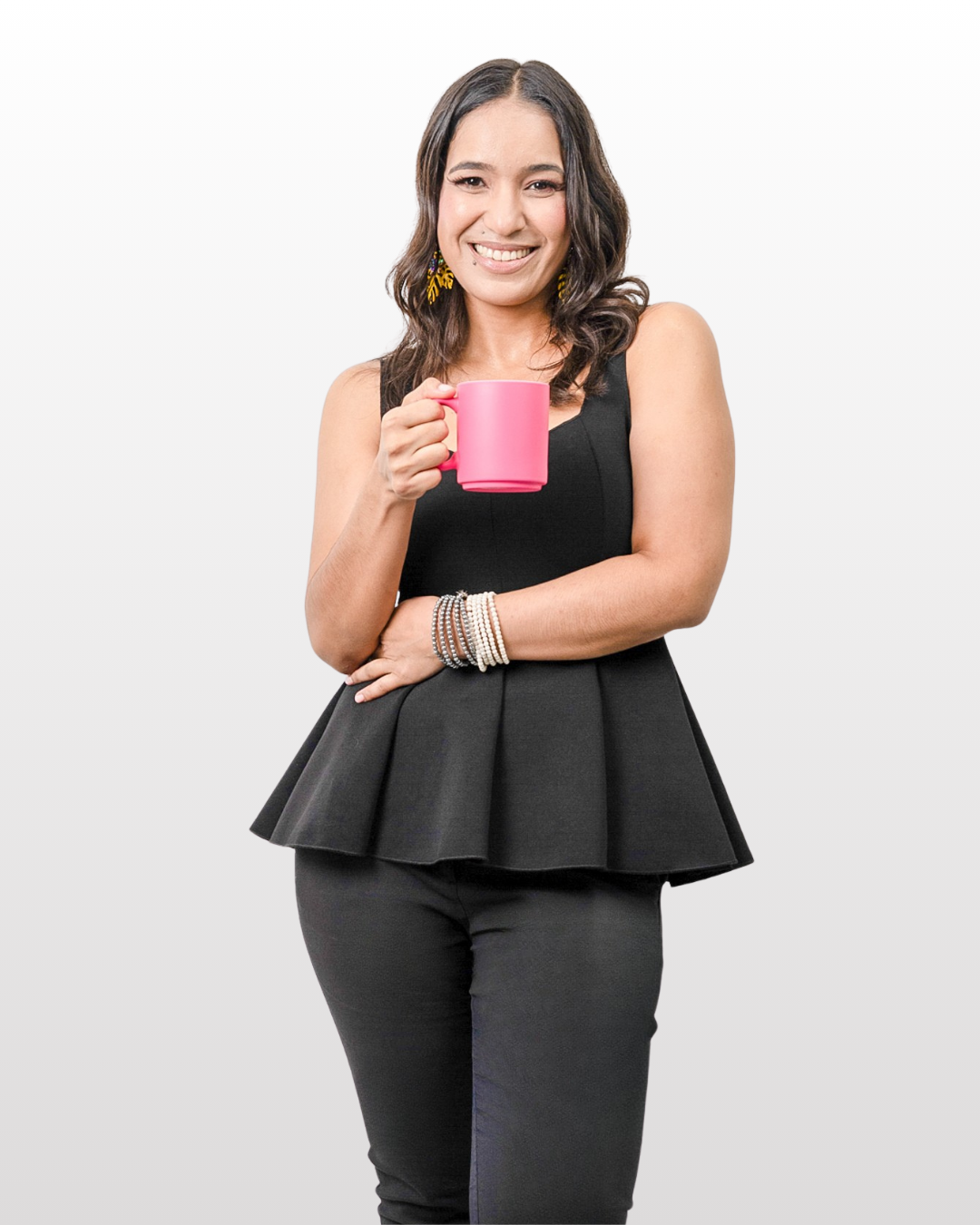 Mujer sonriendo con vestido negro y aretes amarillos, sosteniendo una taza rosa.  Es asesora de imagen.