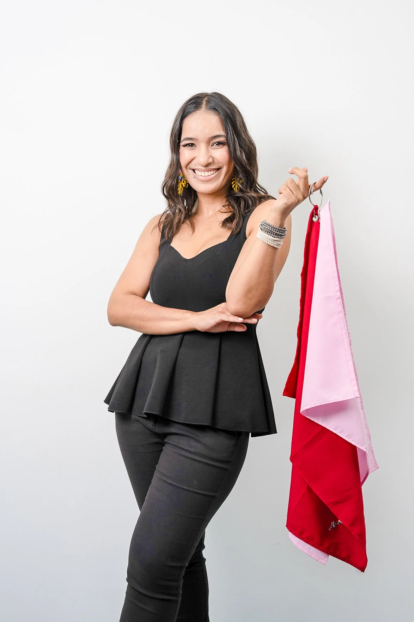 Mujer sonriendo con ropa elegante sosteniendo banderas de colores rojo y rosa.