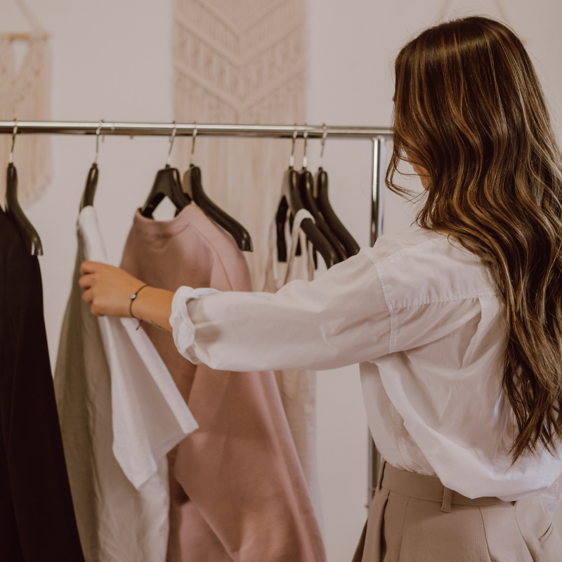 Mujer con cabello largo revisando ropa en una tienda de moda