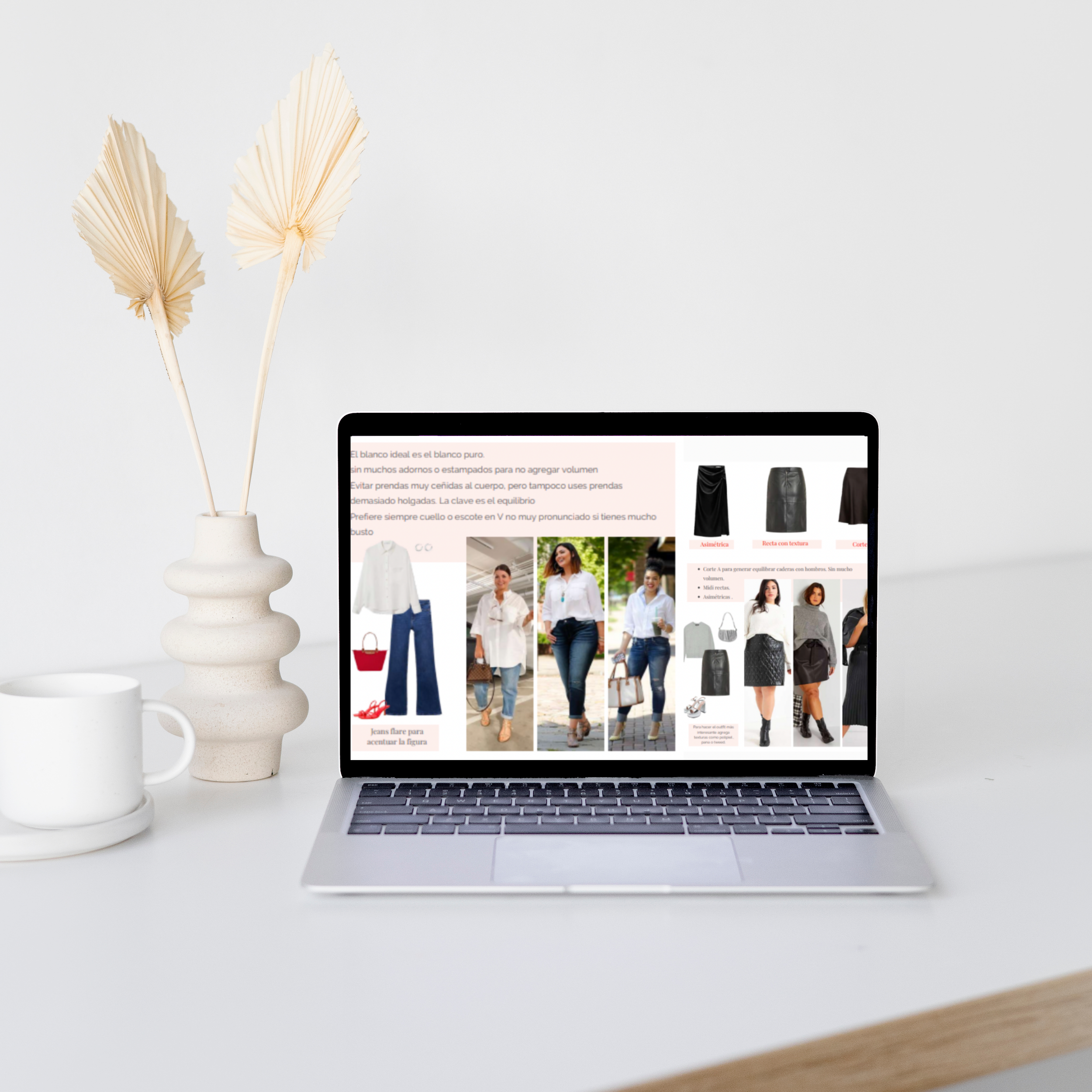 Una laptop en un escritorio blanco con una pantalla que muestra un blog de moda y ropa, acompañada de un jarrón con hojas secas y una taza blanca.