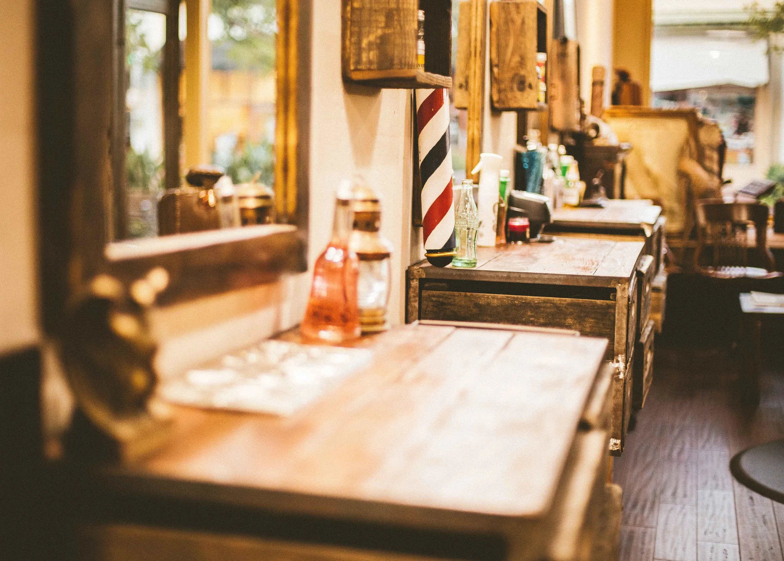 Inside a rustic cafe or bar, wooden counter with bottles, barber pole, and vintage decor.