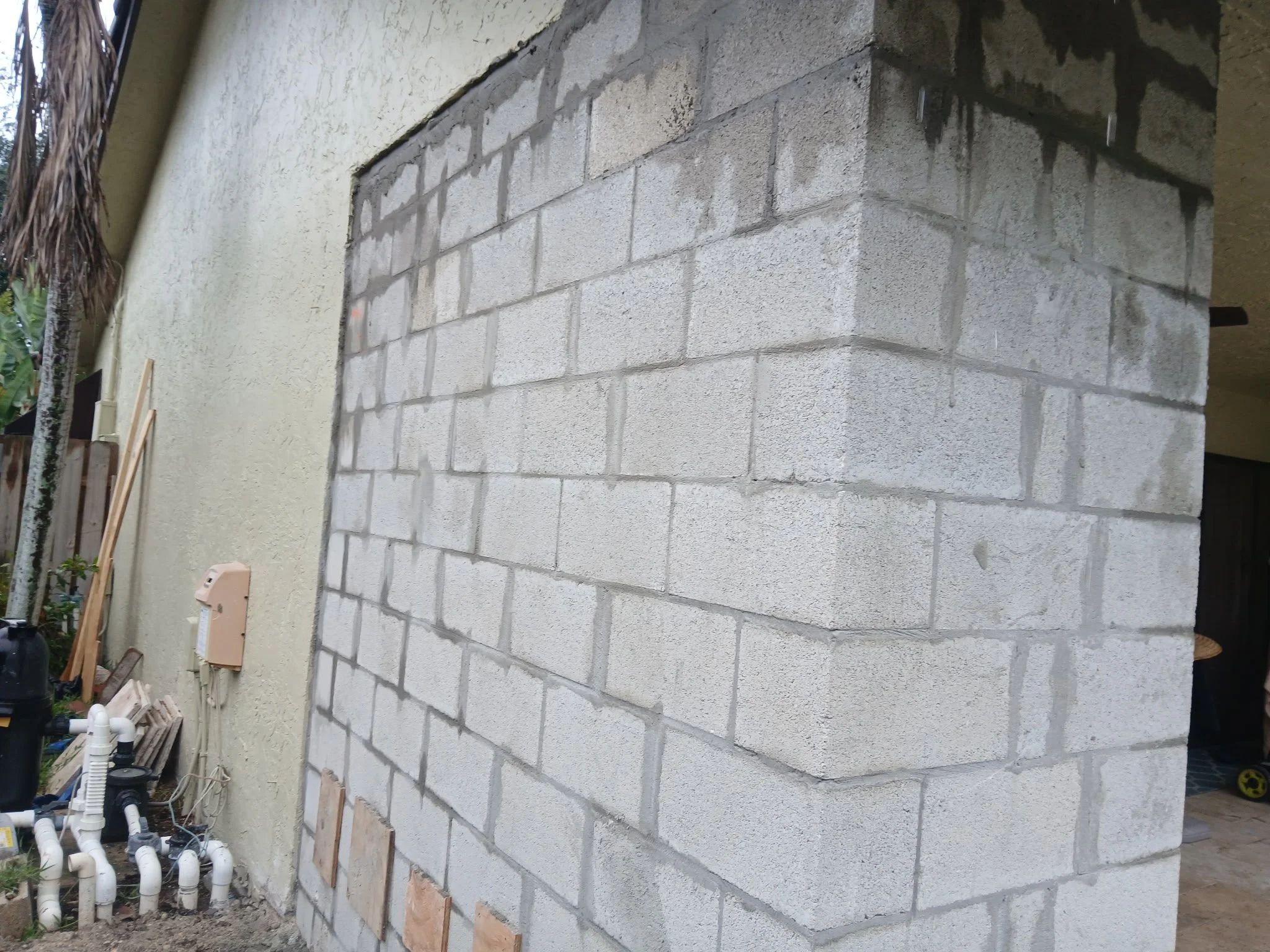 A partially constructed cinder block wall next to an existing stucco wall