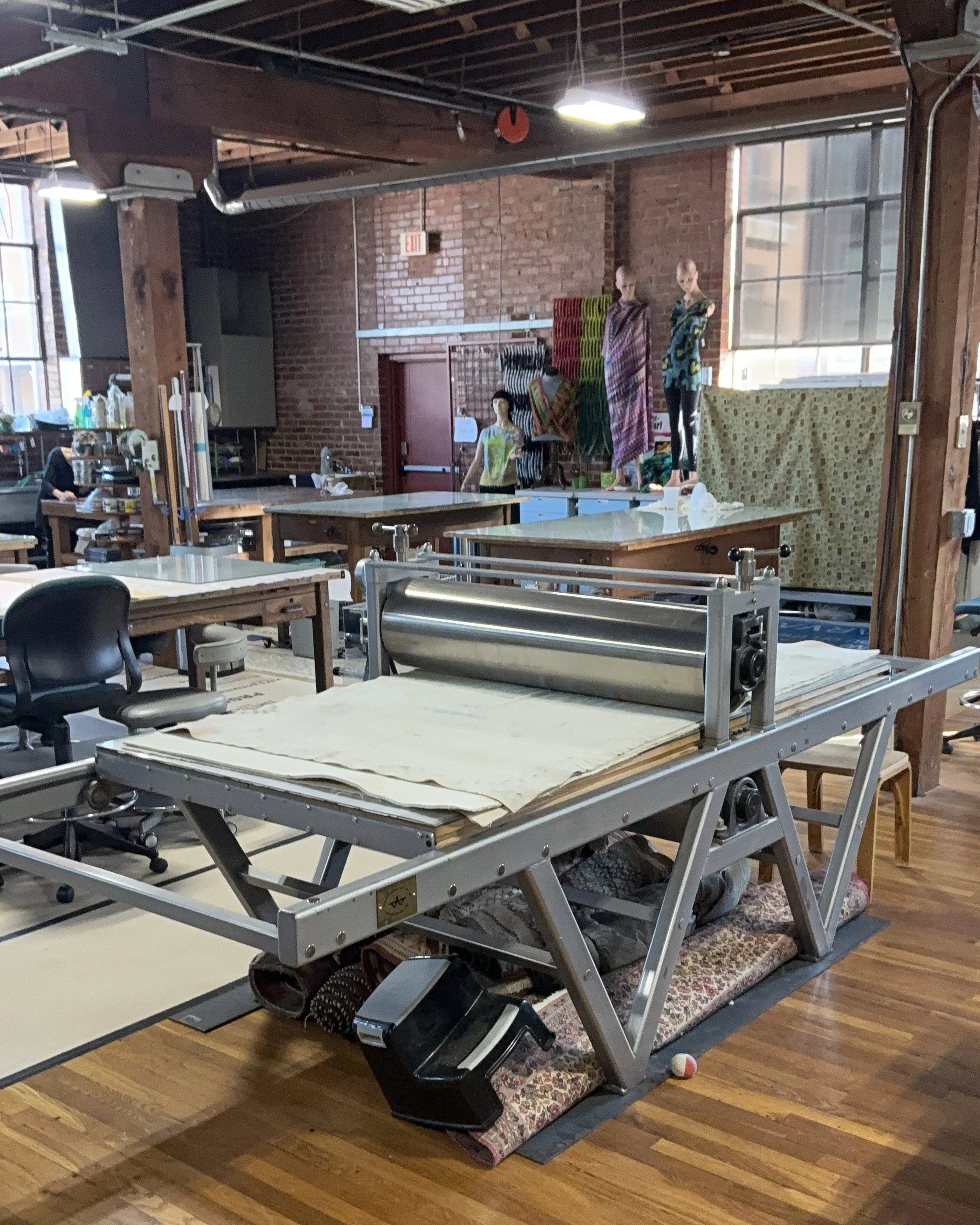 a Takach etching press is a large exposed brick warehouse with inking surfaces and work tables surround it