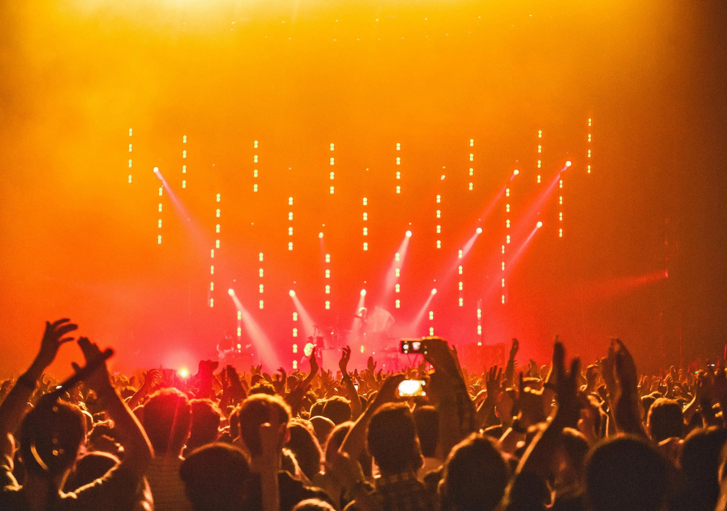 Crowd at a concert with bright red stage lights and people dancing.