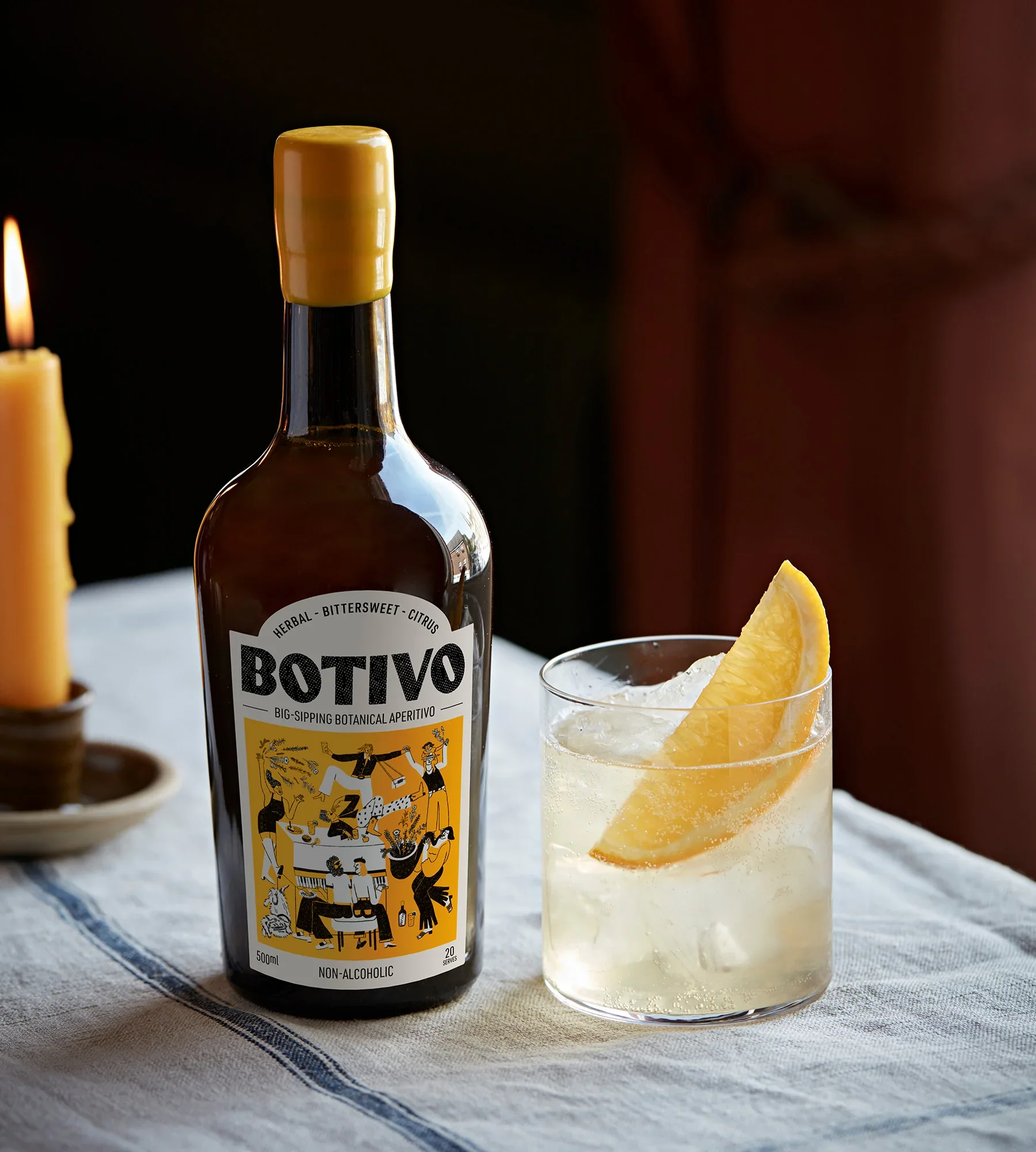 Bottle of non-alcoholic herbal bittersweet citrus beverage and a glass filled with a citrus cocktail garnished with a lemon wedge.