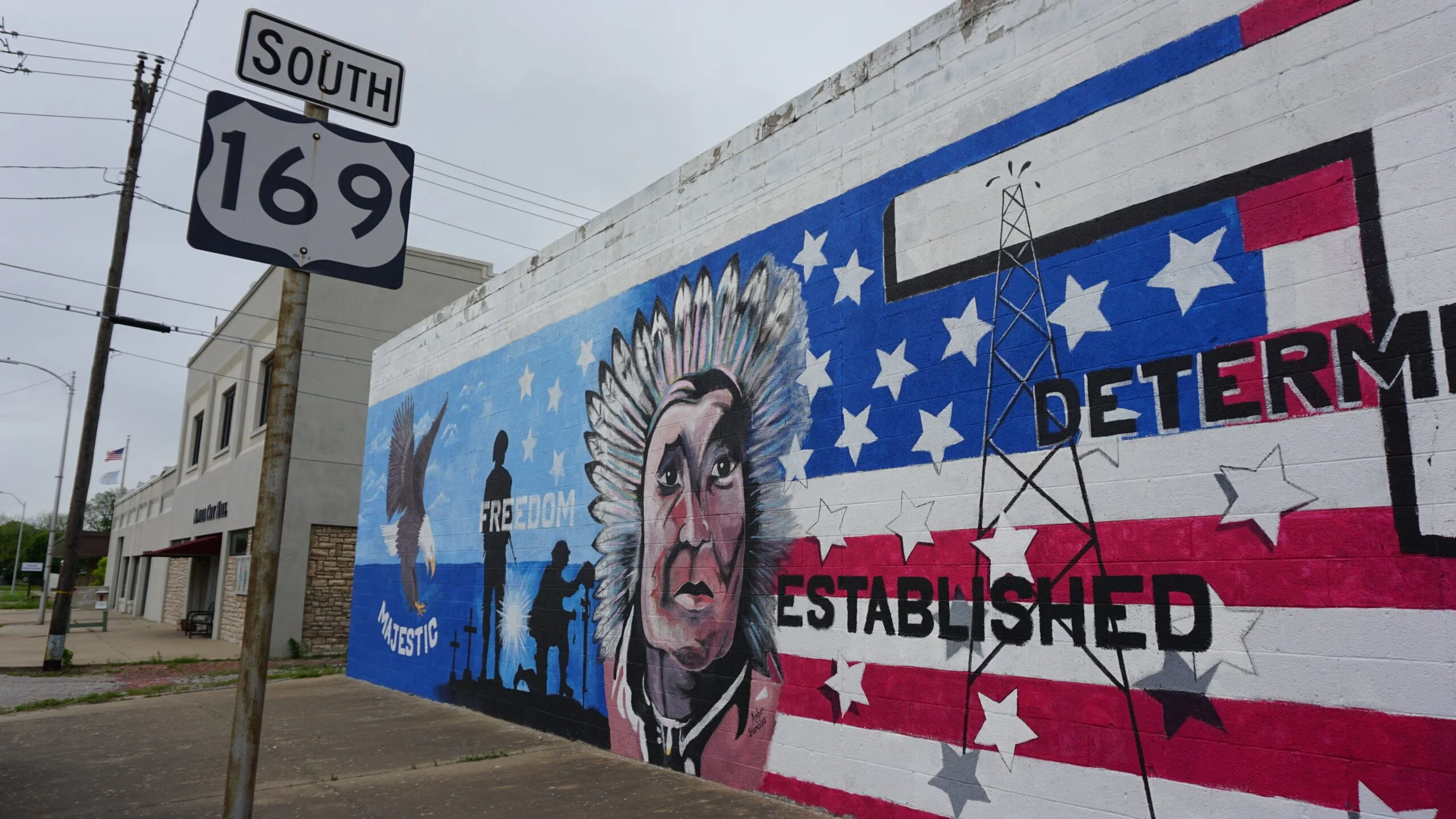 Street mural depicting a Native American man and an eagle with American flag-inspired background, featuring the words "FREEDOM," "MAJESTIC," "DETERMINED," and "ESTABLISHED."