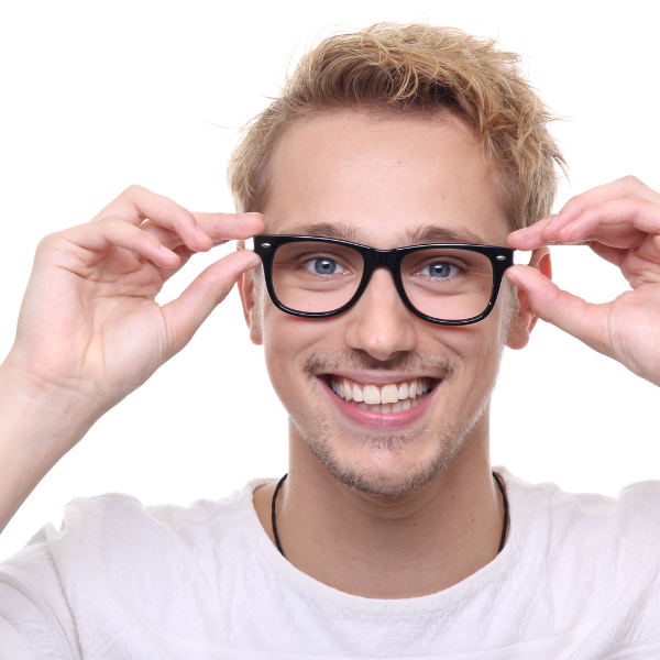 A smiling young man with blond hair and glasses adjusting his eyeglasses against a white background.