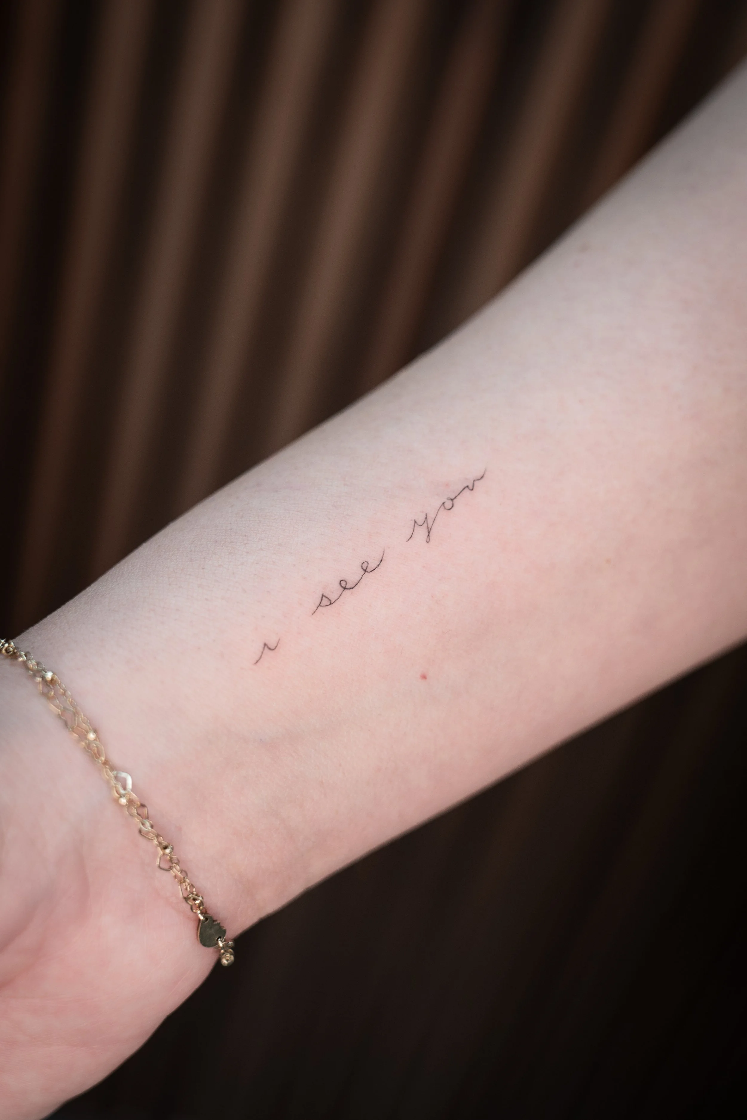 A tattoo on a person's forearm that reads 'I see you' in cursive script.