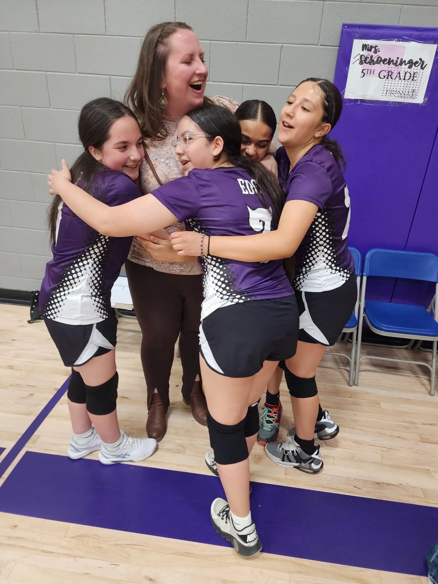 Kristin in the middle of a group hug with the volleyball players she coaches