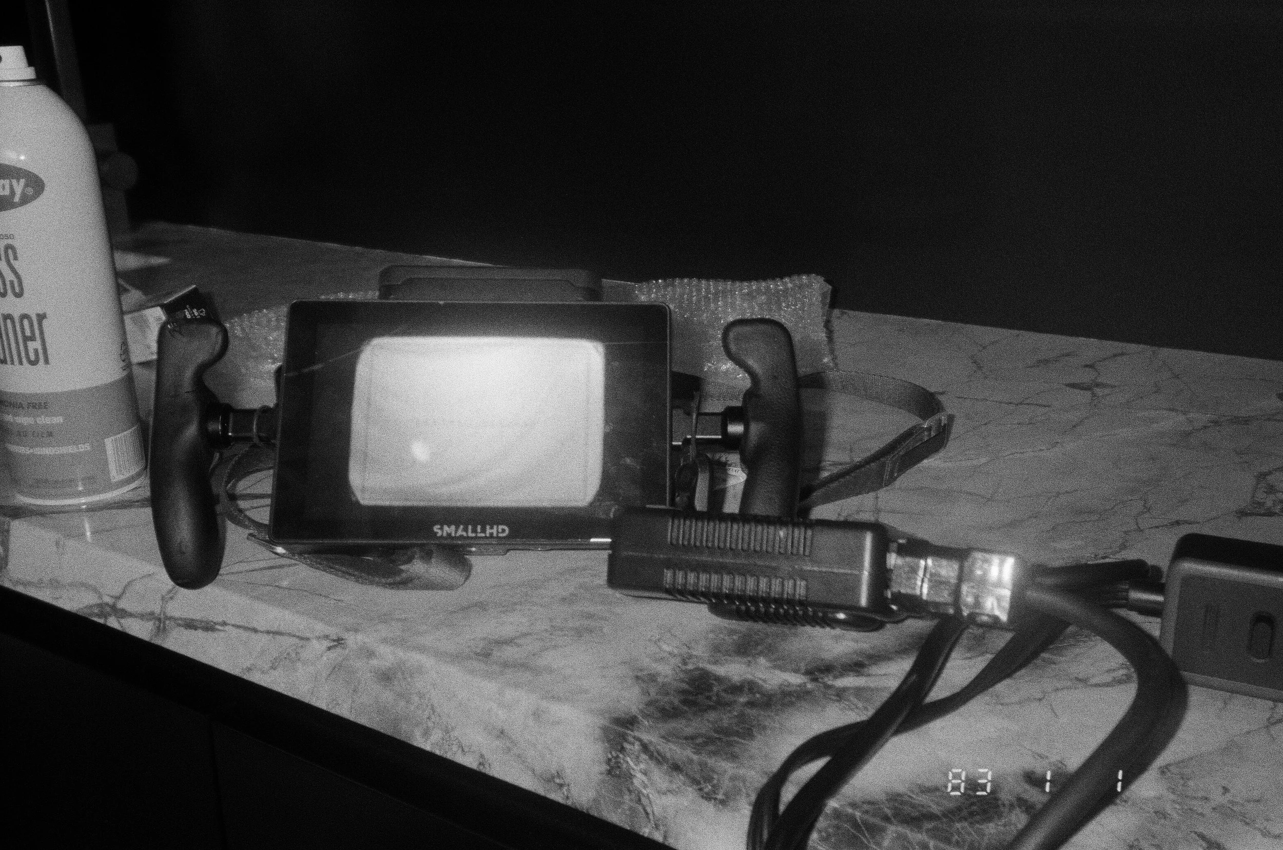 A SmallHD monitor and cables laid out on a marble counter beside lens cleaner.