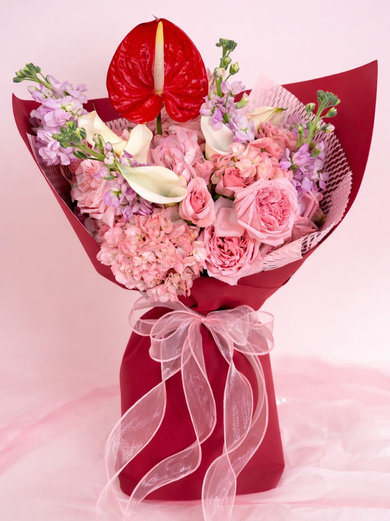 Soft pinks, creamy whites, and that bold pop of red ❤️ This bouquet is giving romantic, feminine, and effortlessly luxe all at once.

Featuring lush garden roses, hydrangeas, delicate stock, elegant calla lilies (requested by the client) and a statem