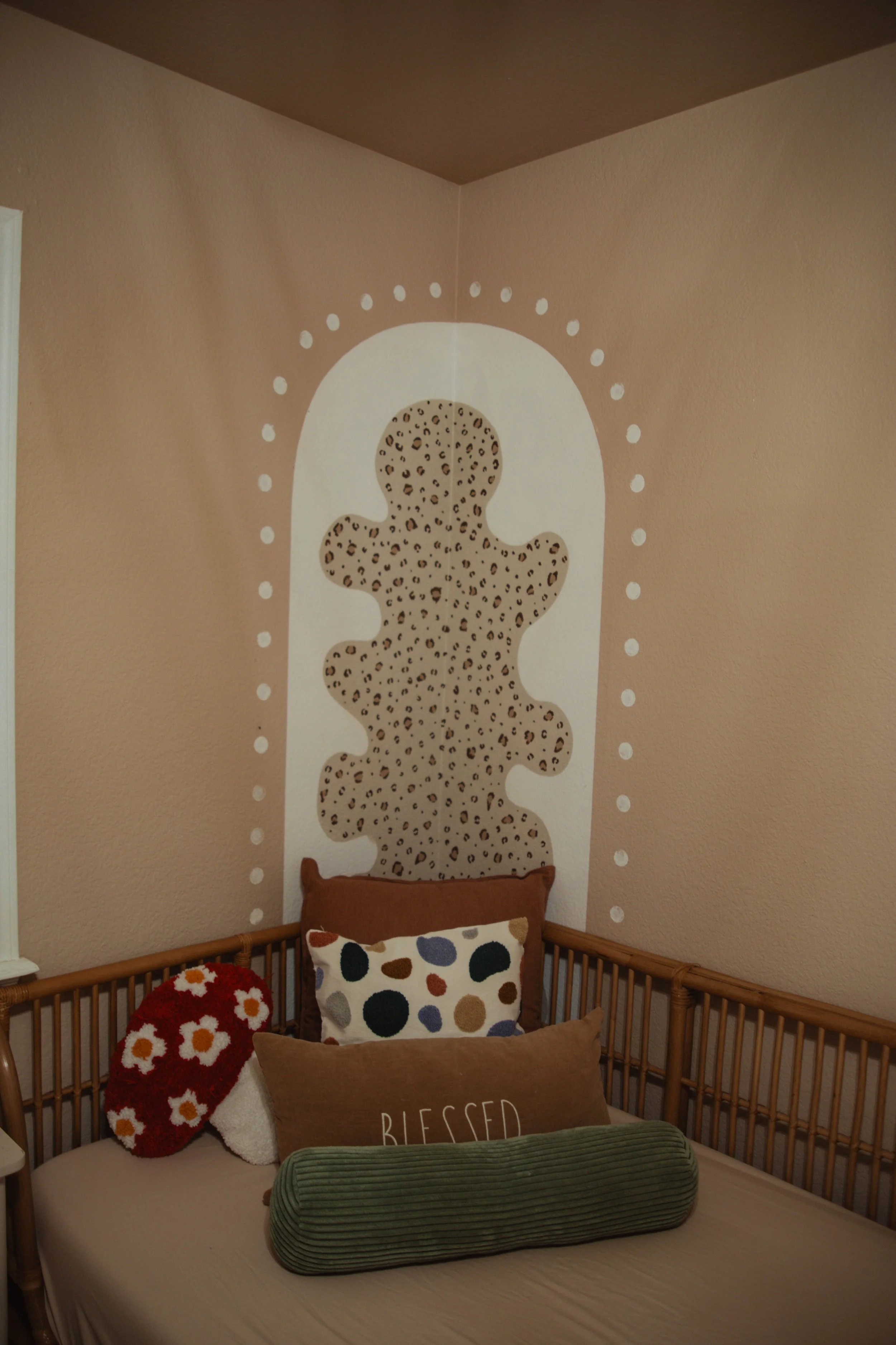Corner of a bedroom with pillows on a bed, featuring a wall decoration of a leopard print teddy bear shape with a white background.