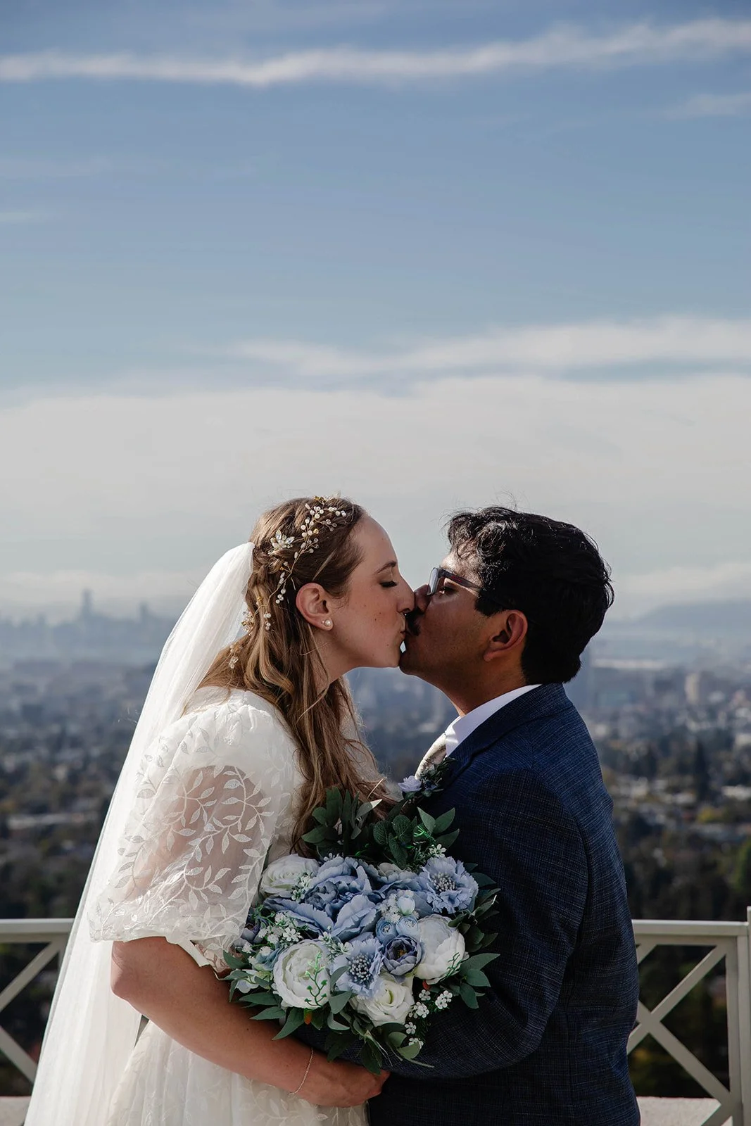 Bride and groom kiss with the city in the backdrop