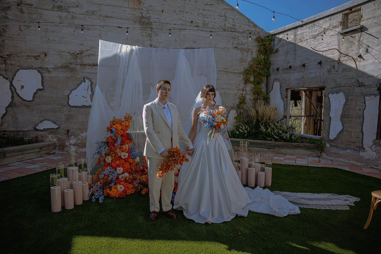 A couple poses in a European inspired wedding venue with colorful florals