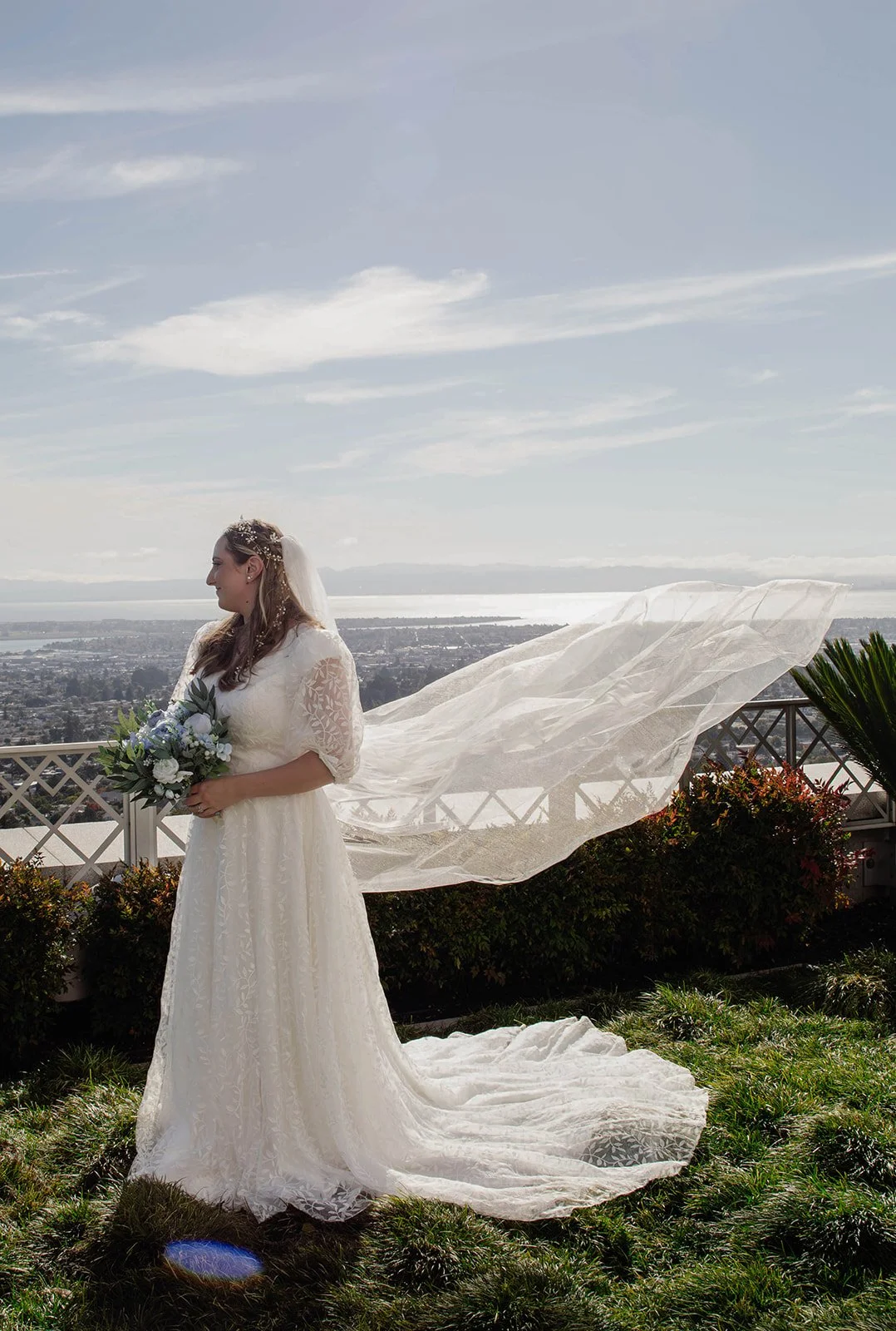 Bride standing in her dress and veil overlooking the city