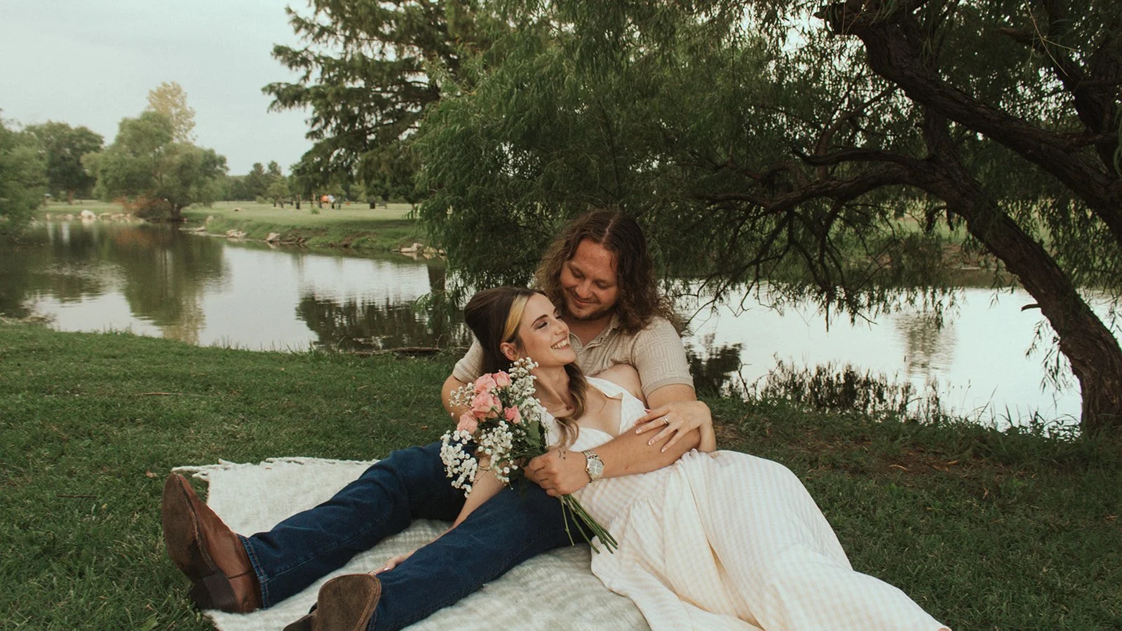 Couple snuggles up on a picnic blanket near the river