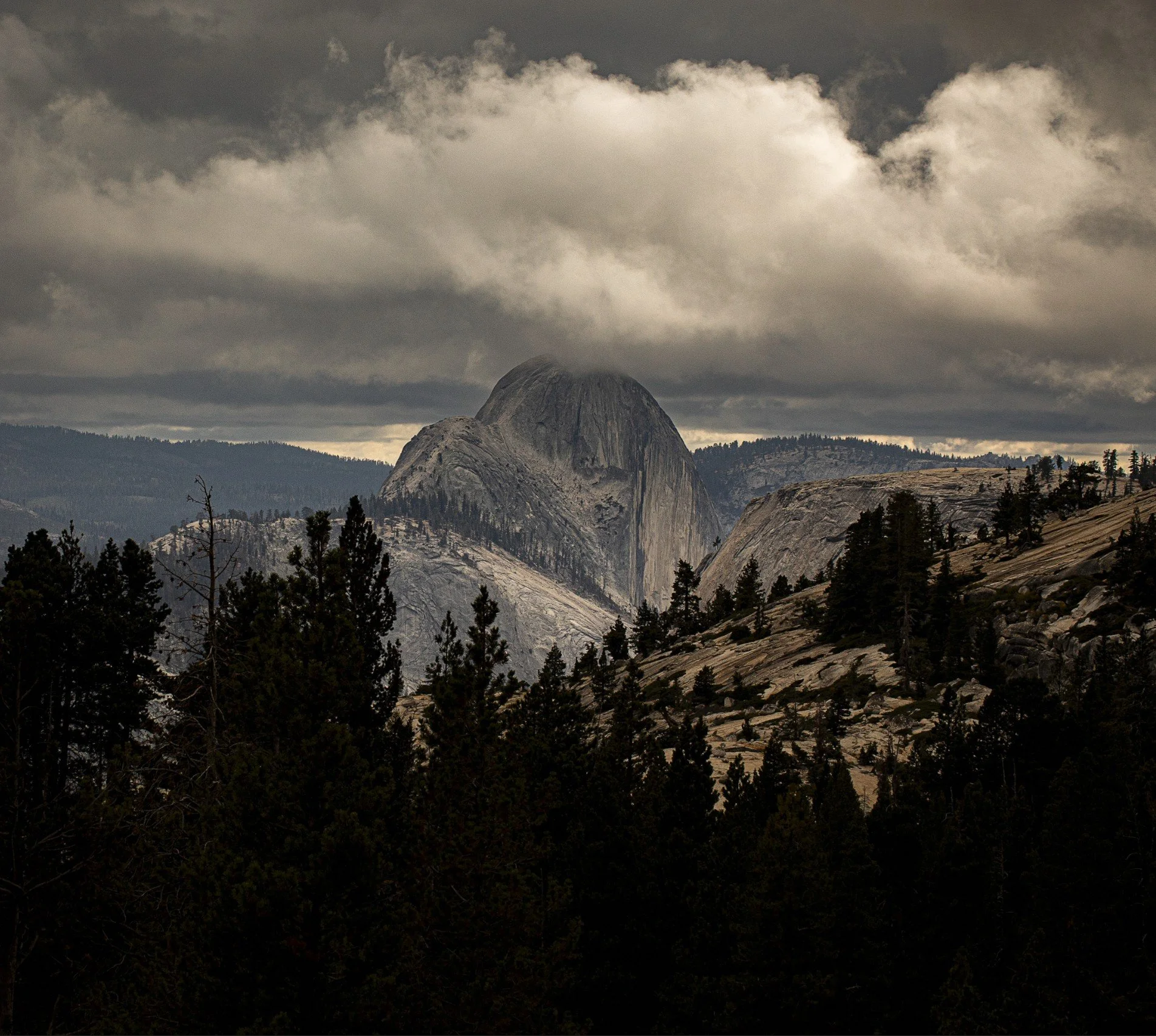 A better edited version of a mountain landscape with Half Dome in Yosemite National Park in the background with trees and cloudy sky