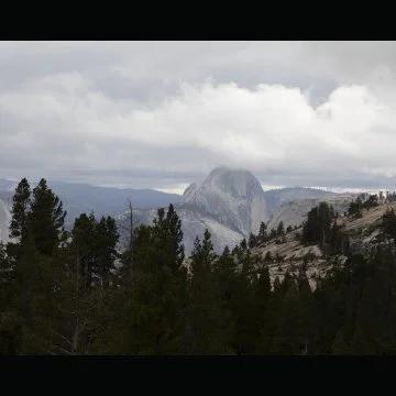 Mountain landscape with Half Dome in Yosemite National Park in the background with trees and cloudy sky