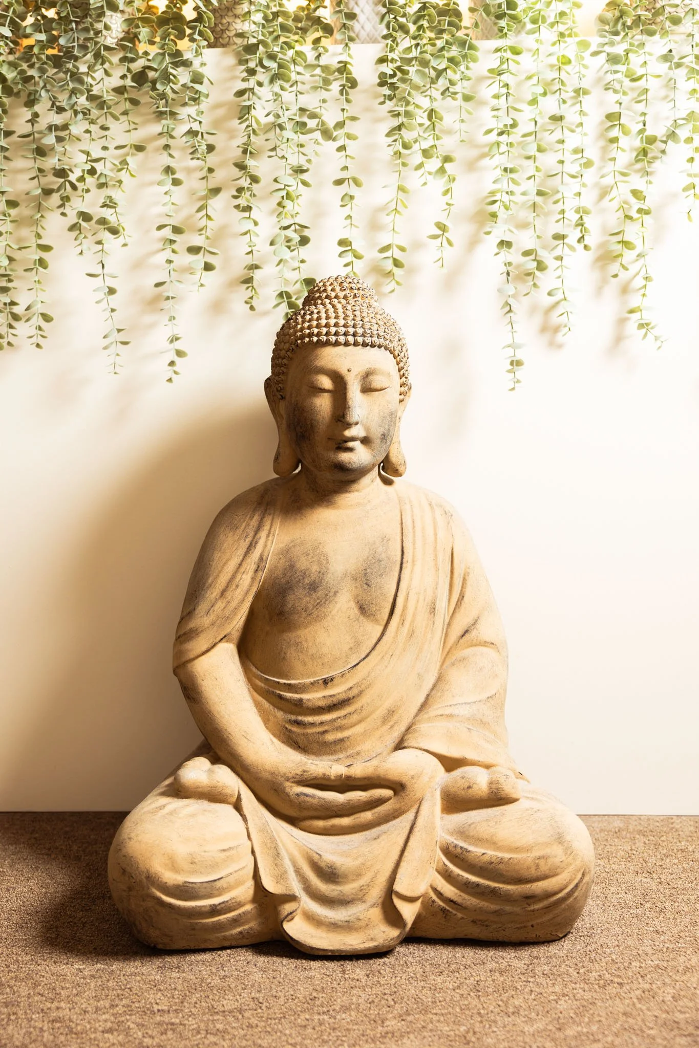 statue of budda in a spa with plants above it