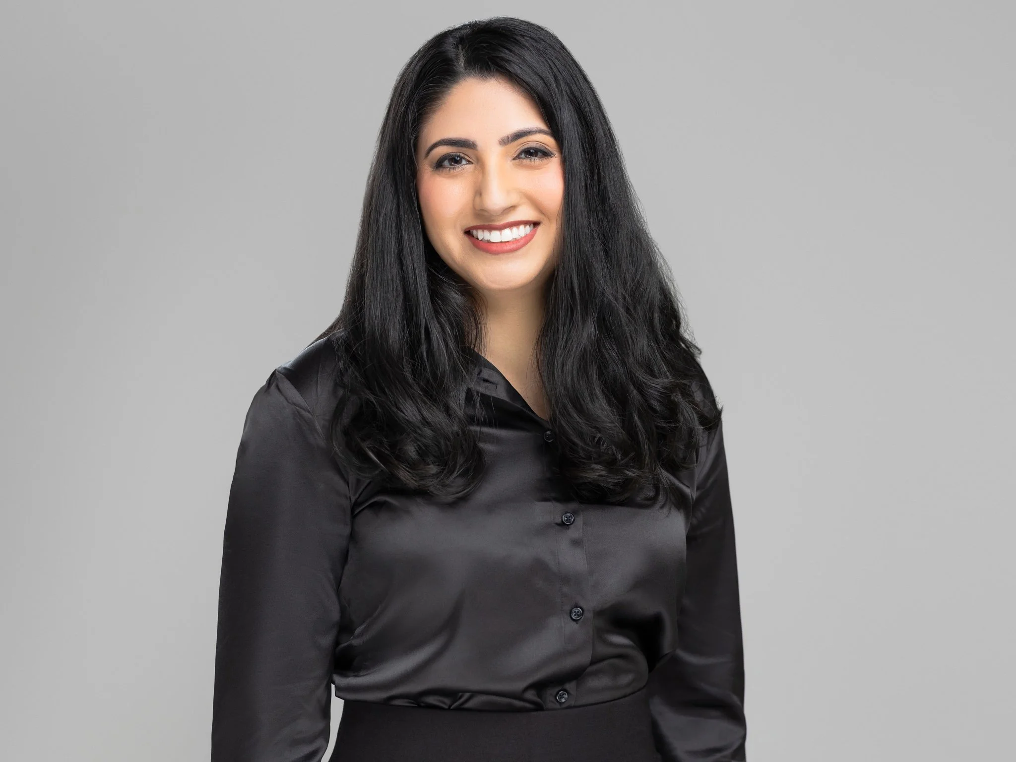 Portrait of a young woman in a black silk blouse smiling at the camera.