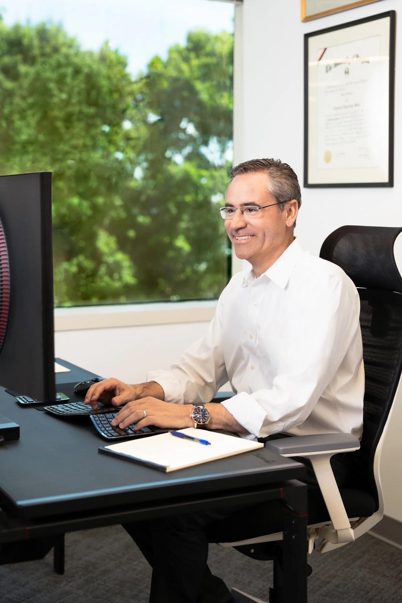 One attorney sitting at a desk smiling while looking at a computer screen