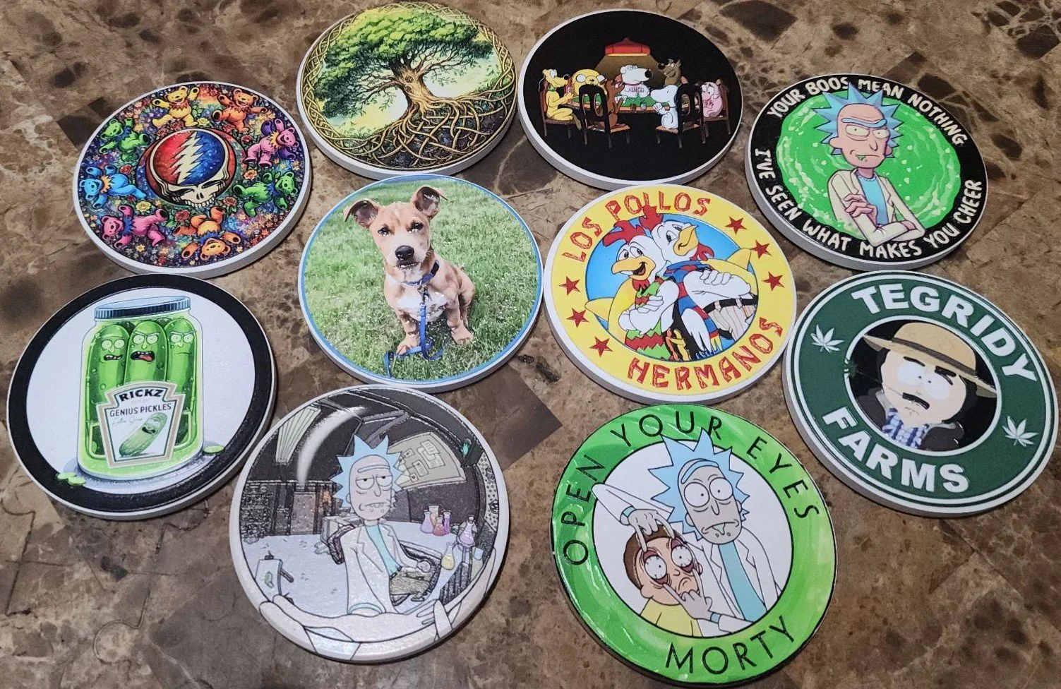 A collection of round Coasters featuring various illustrations including cartoon characters, animals, and pop culture references, spread out on a marble surface.