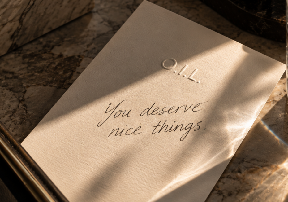 A letter on a marble surface with the embossed text 'O.I.L' and handwritten message 'You deserve nice things'.