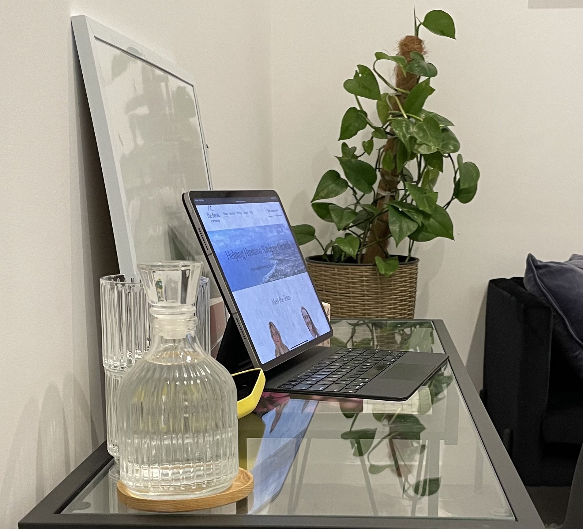 A person sitting on a bed using a silver laptop with a black keyboard, wearing light pink pajamas, on white sheets.
