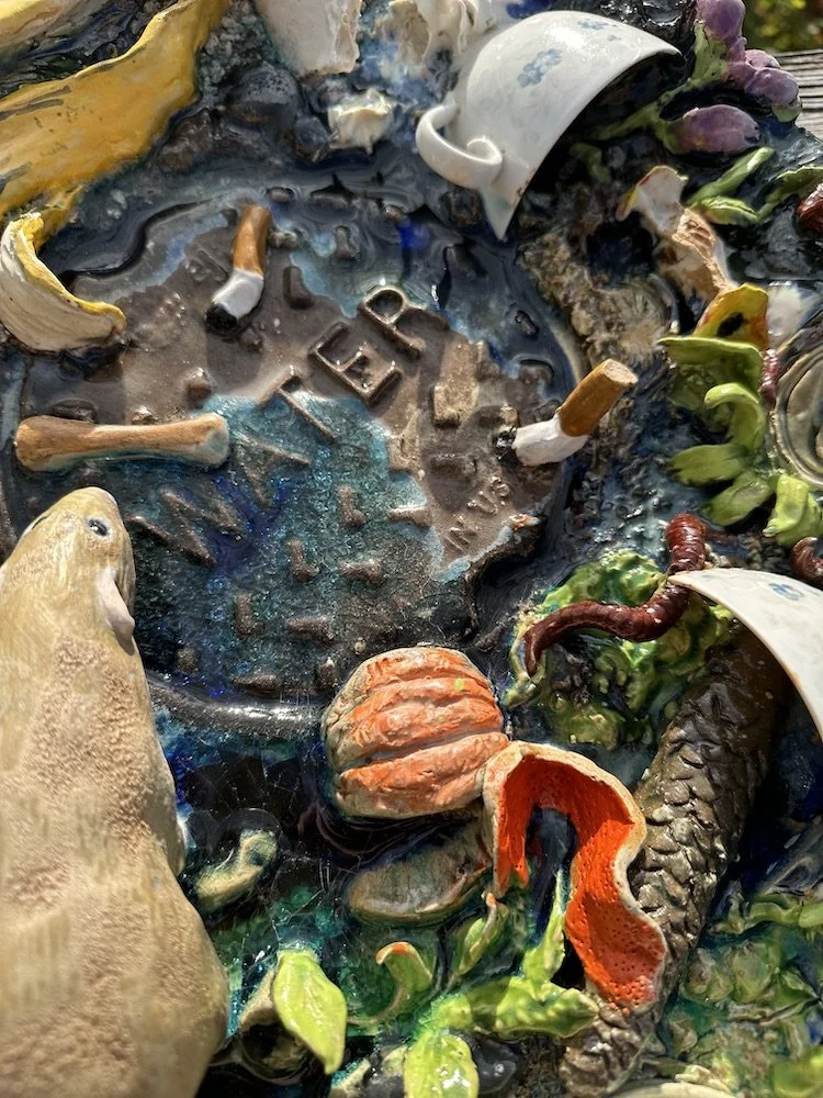 A detail of a platter with various garbage, broken cup, and orange peel