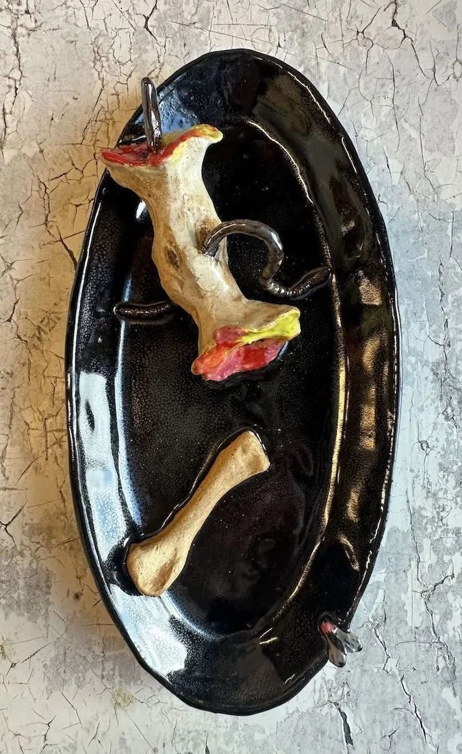 A black oval tray holding a faux animal bone and an apple core.