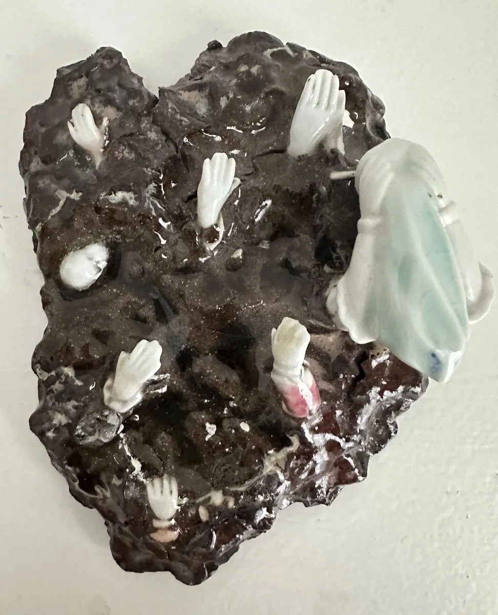 Chocolate cake decorated with small white plastic hands and a large white plastic head of a woman with long hair.